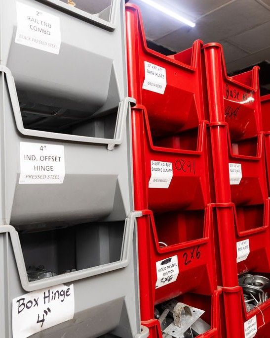 Rows of gray and red storage bins labeled with parts names, inside a warehouse.