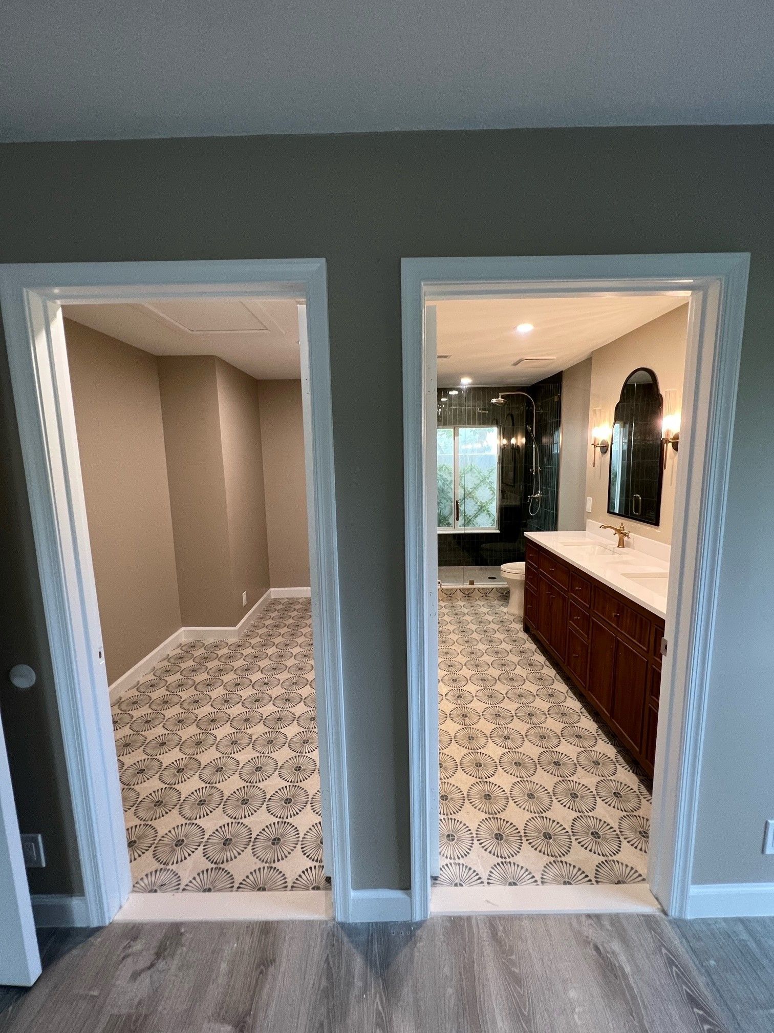 Two doorways reveal rooms with patterned floors. The right room shows a vanity and shower. The left room is empty.