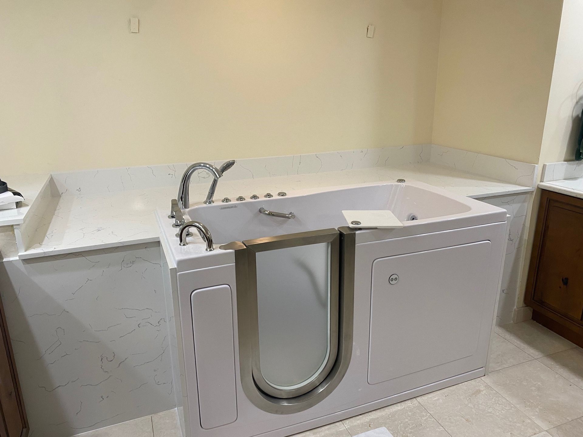 White walk-in bathtub with a door, set in a bathroom with beige walls.