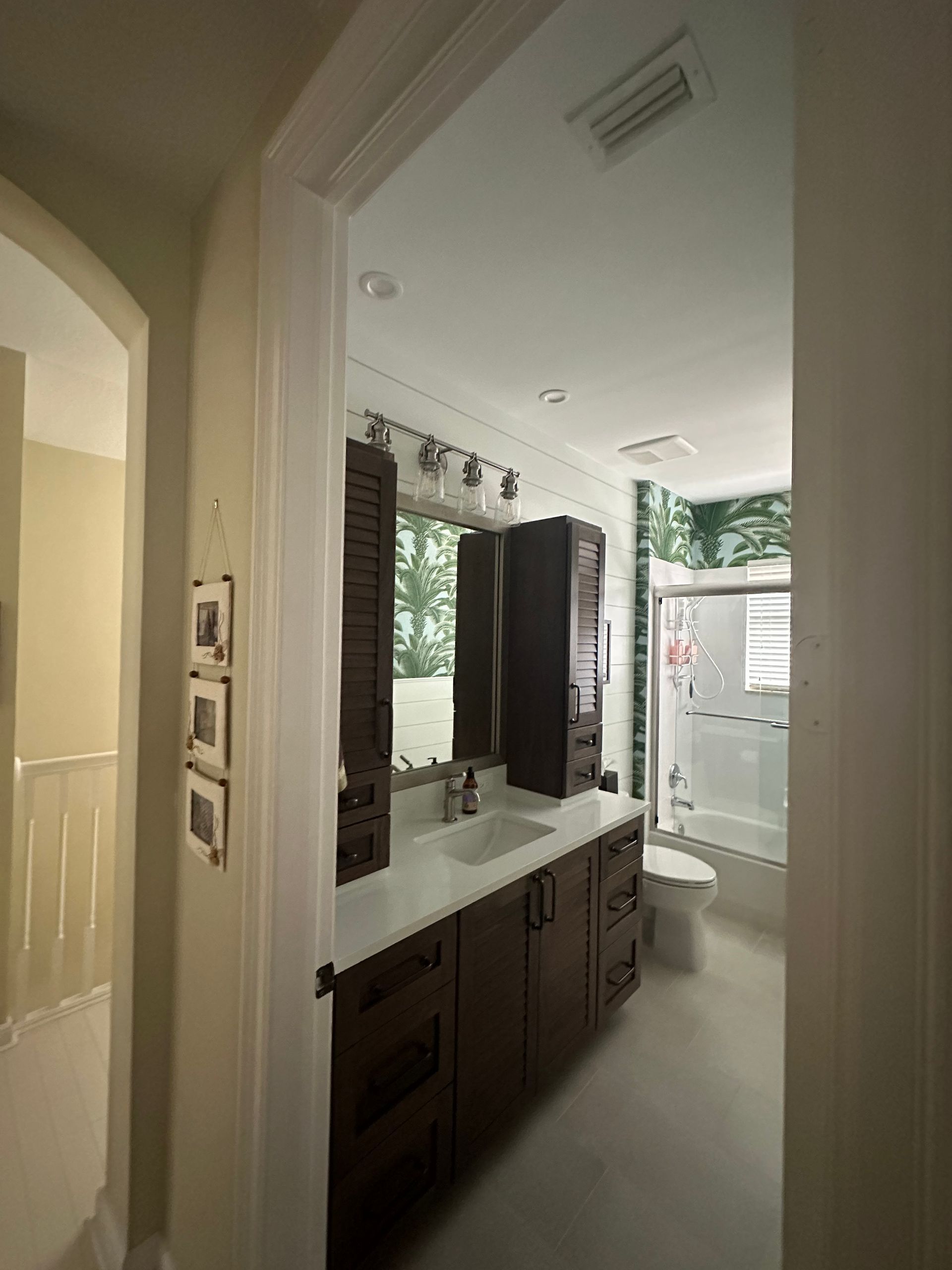 Bathroom with dark wood vanity, white countertop, and a shower with a forest-themed mural.