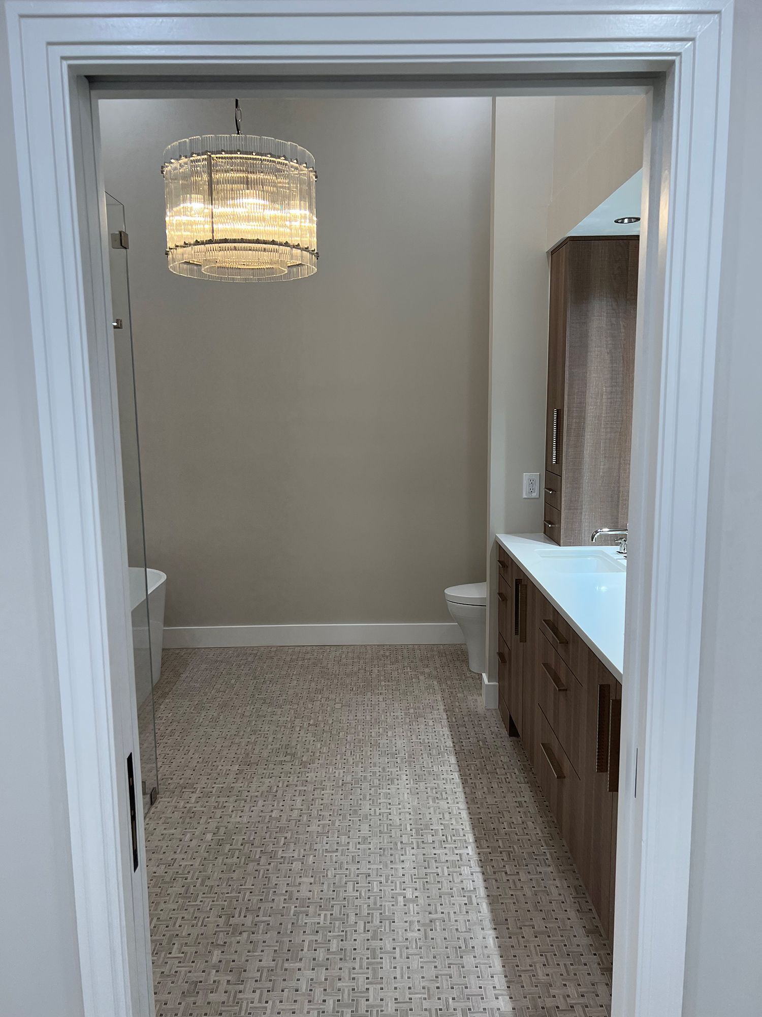 Bathroom interior with a patterned floor, chandelier, and vanity with a mirror.