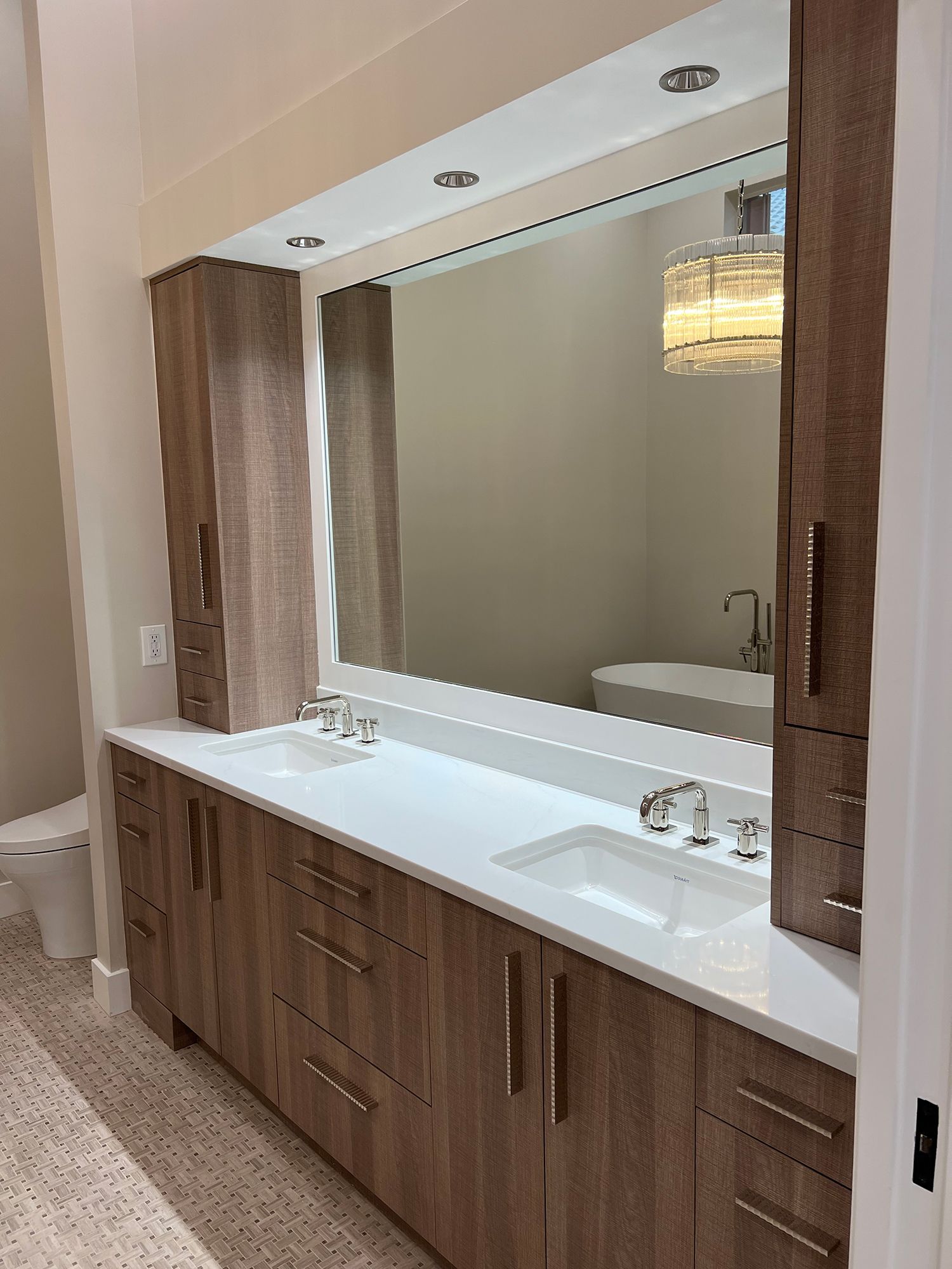 Modern bathroom with double vanity, large mirror, and wood-toned cabinetry.