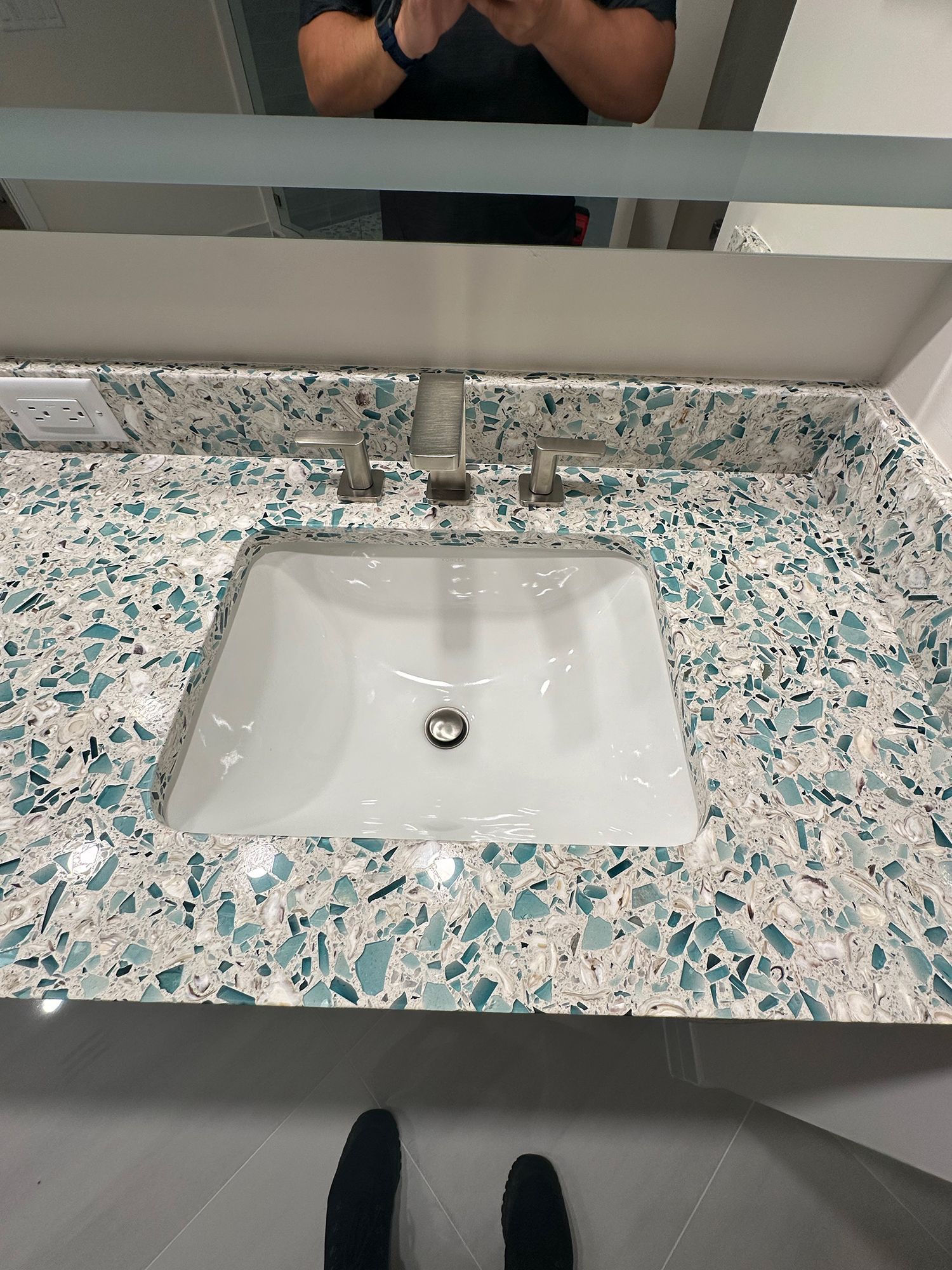 Bathroom vanity with white sink, mosaic blue and white countertop, and silver faucet.