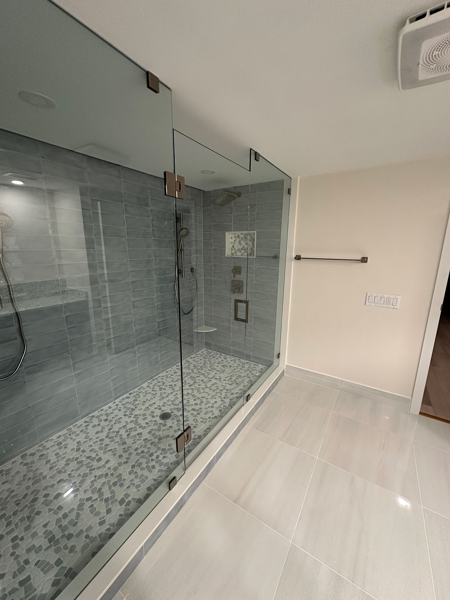 Modern bathroom with glass shower enclosure, gray tile walls and floor, and silver fixtures.