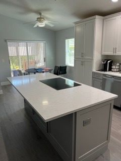 Modern kitchen with large gray island, white cabinets, and built-in stovetop.