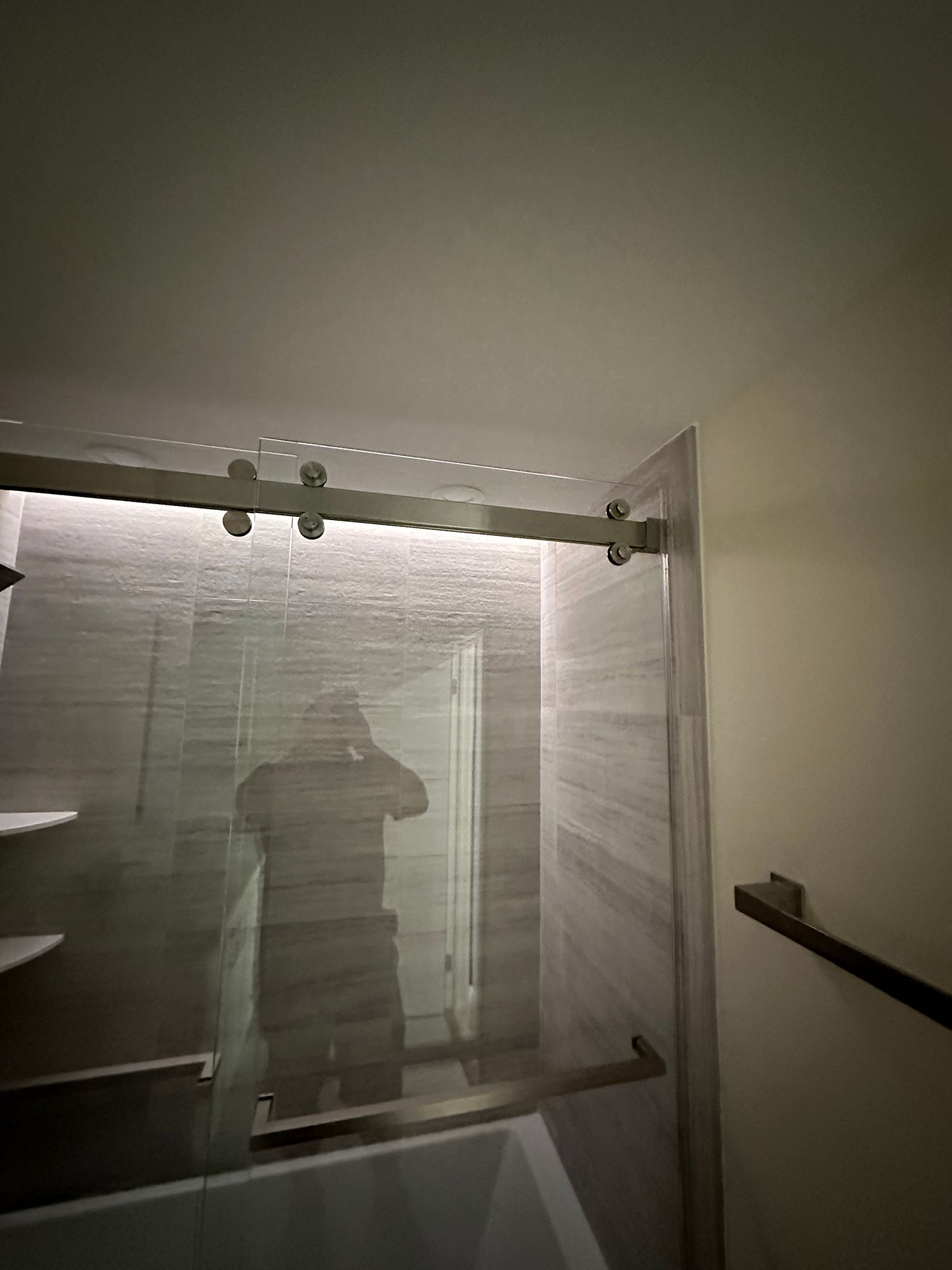 Bathroom shower with glass sliding door and gray tiled walls.