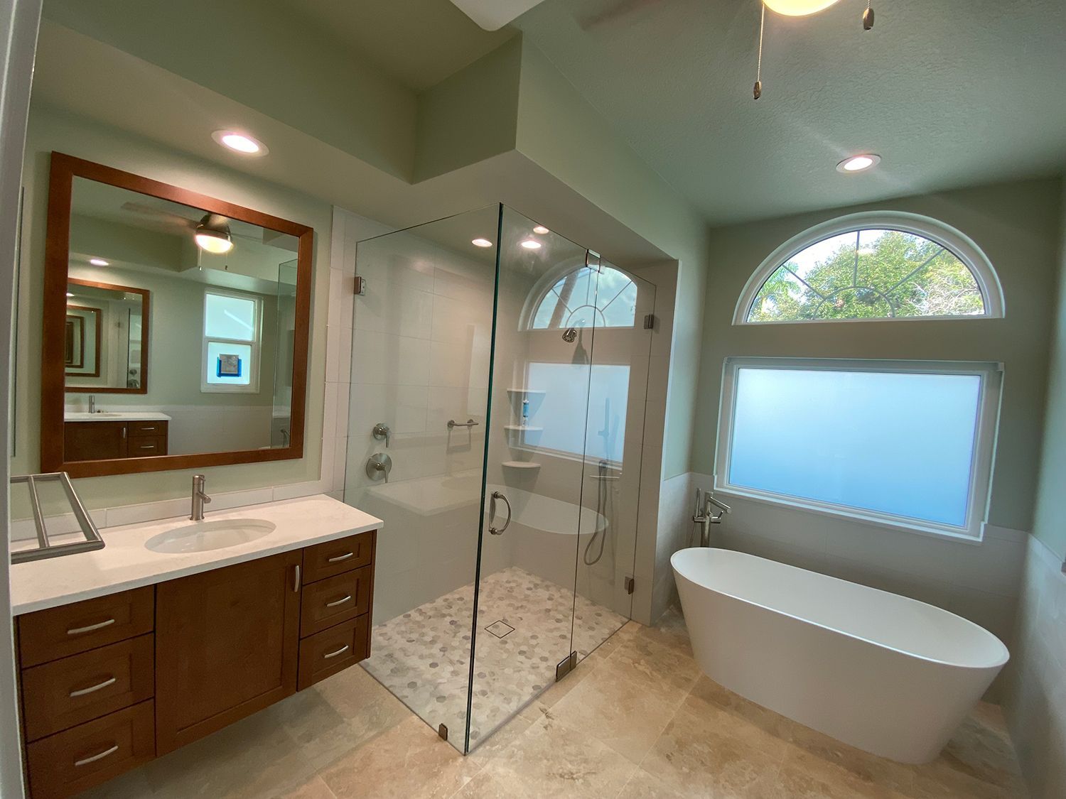 Modern bathroom with a glass shower, soaking tub, and vanity with a large mirror.