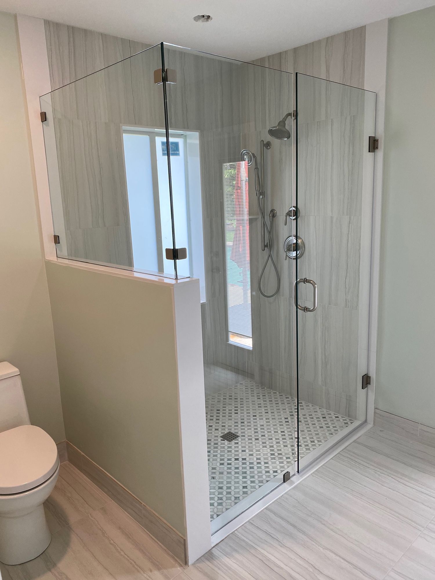 Modern bathroom with glass shower enclosure, tiled walls, and toilet.