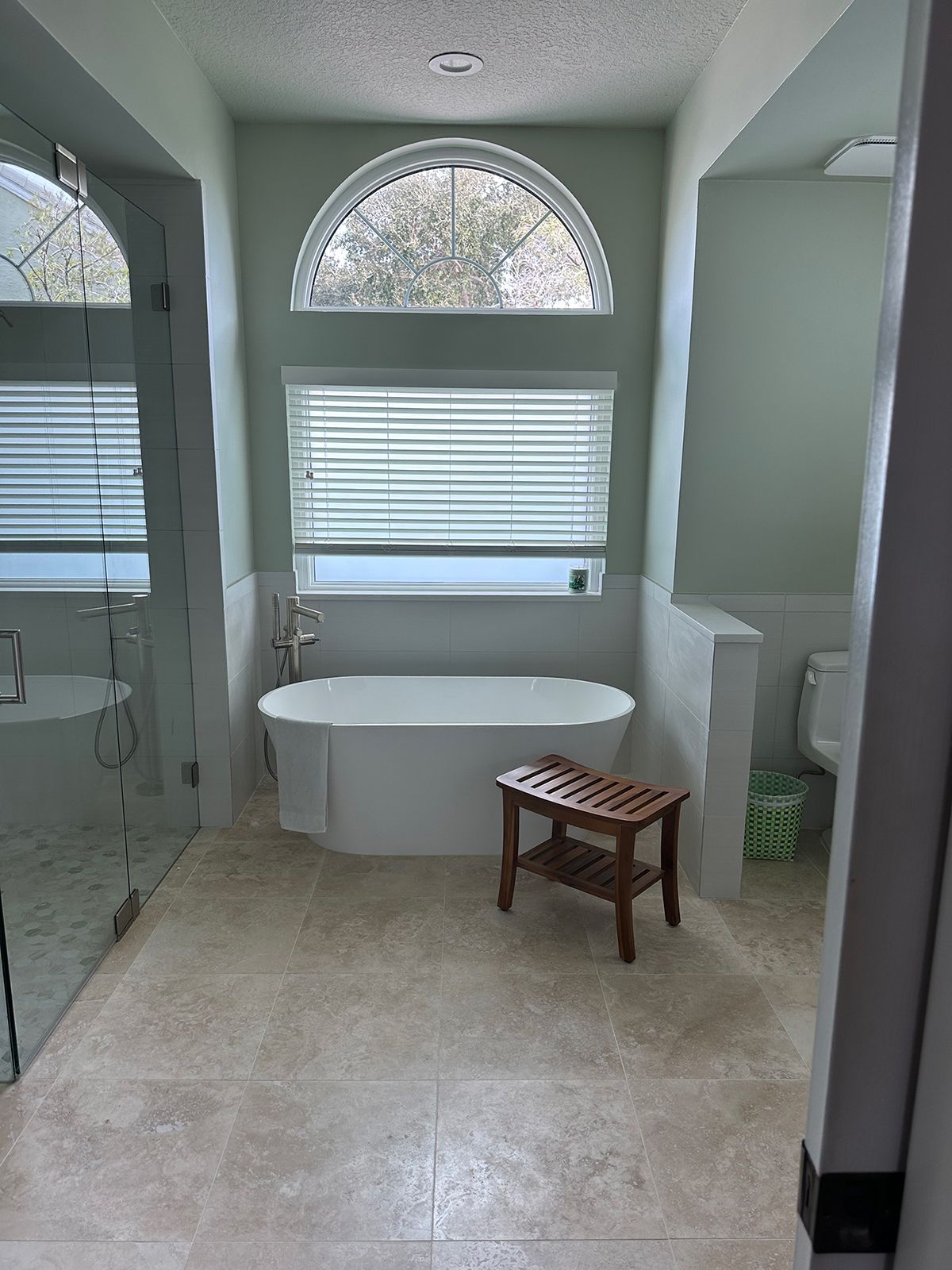 Bathroom with a freestanding tub, glass shower, toilet, and a wooden bench.