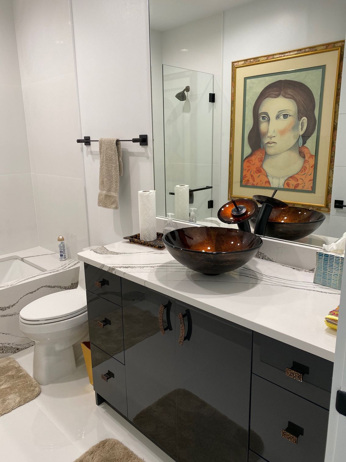 Bathroom with dark cabinets, glass bowl sinks, large mirror, and framed artwork.