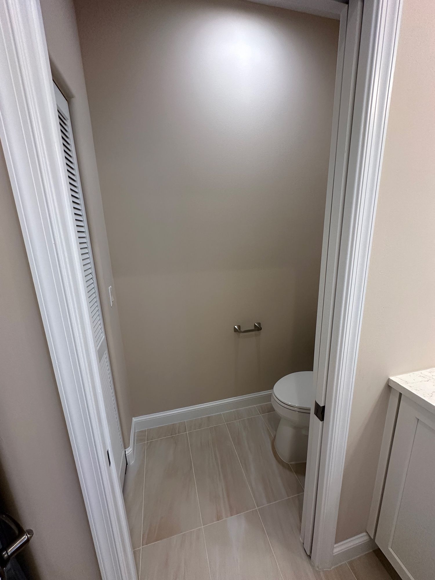 Small bathroom with beige walls, white trim, and toilet.