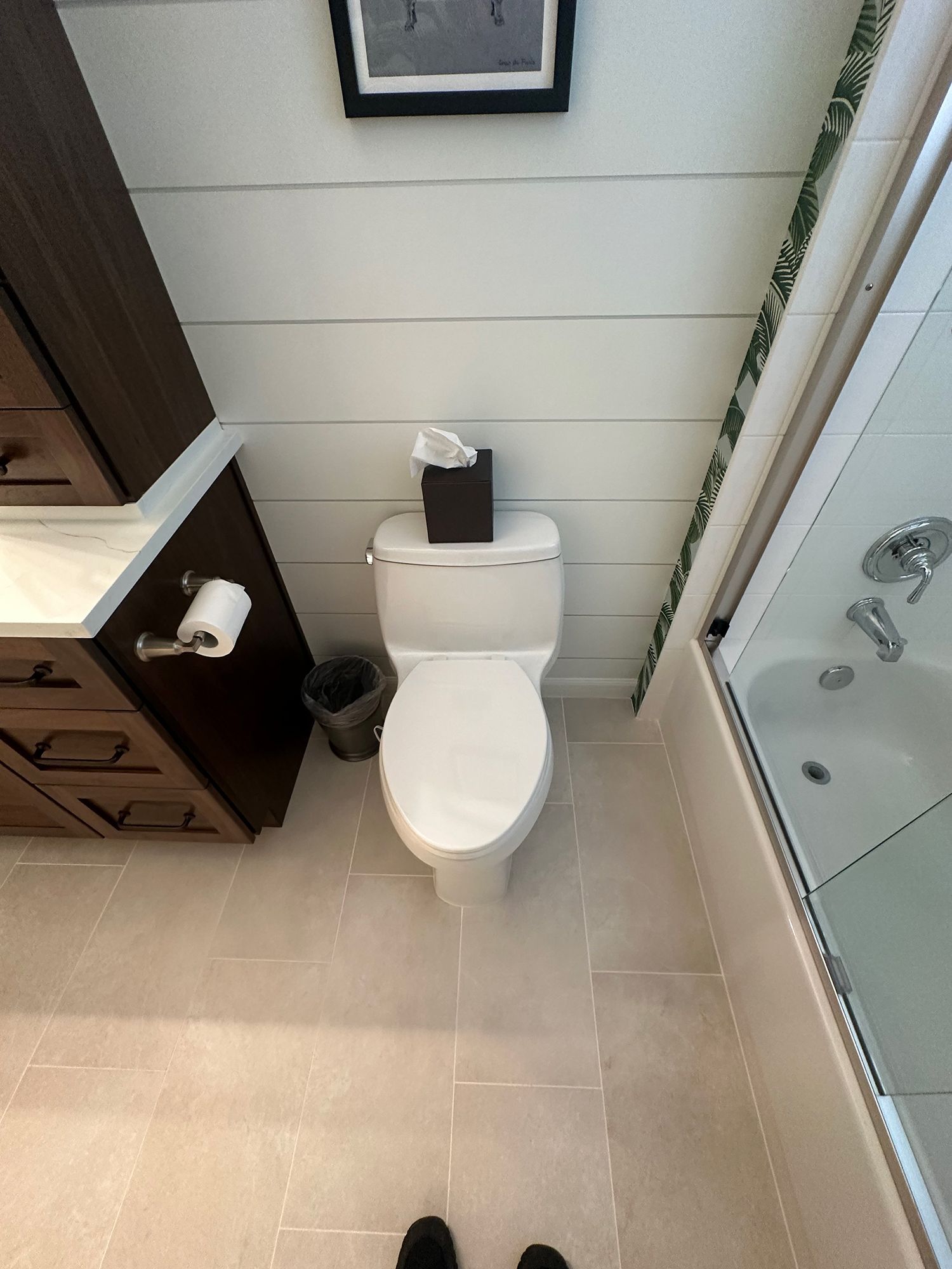 Bathroom with a white toilet, brown cabinet, and a shower.