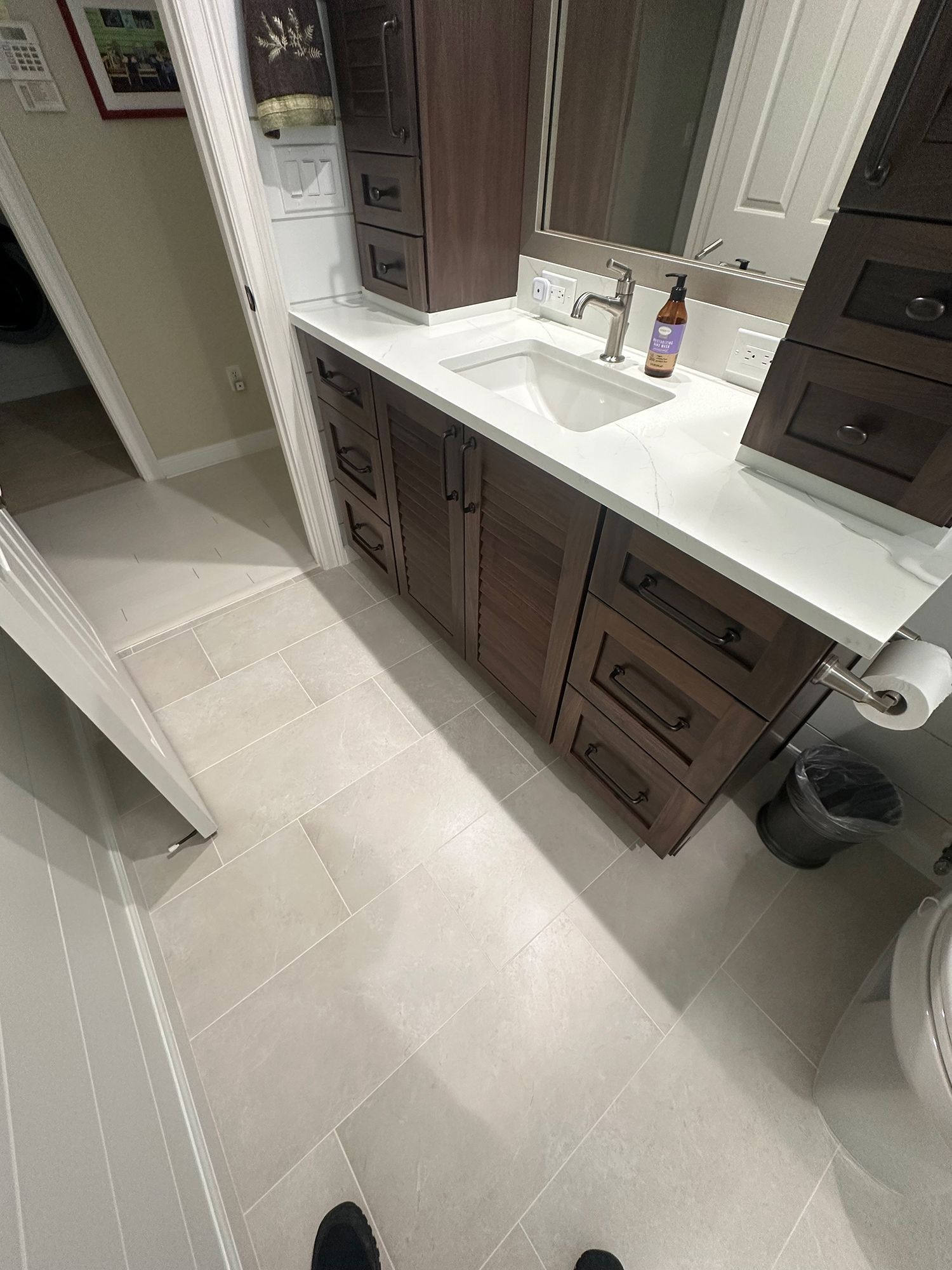 Bathroom with dark brown vanity, white countertop, and gray tiled floor.