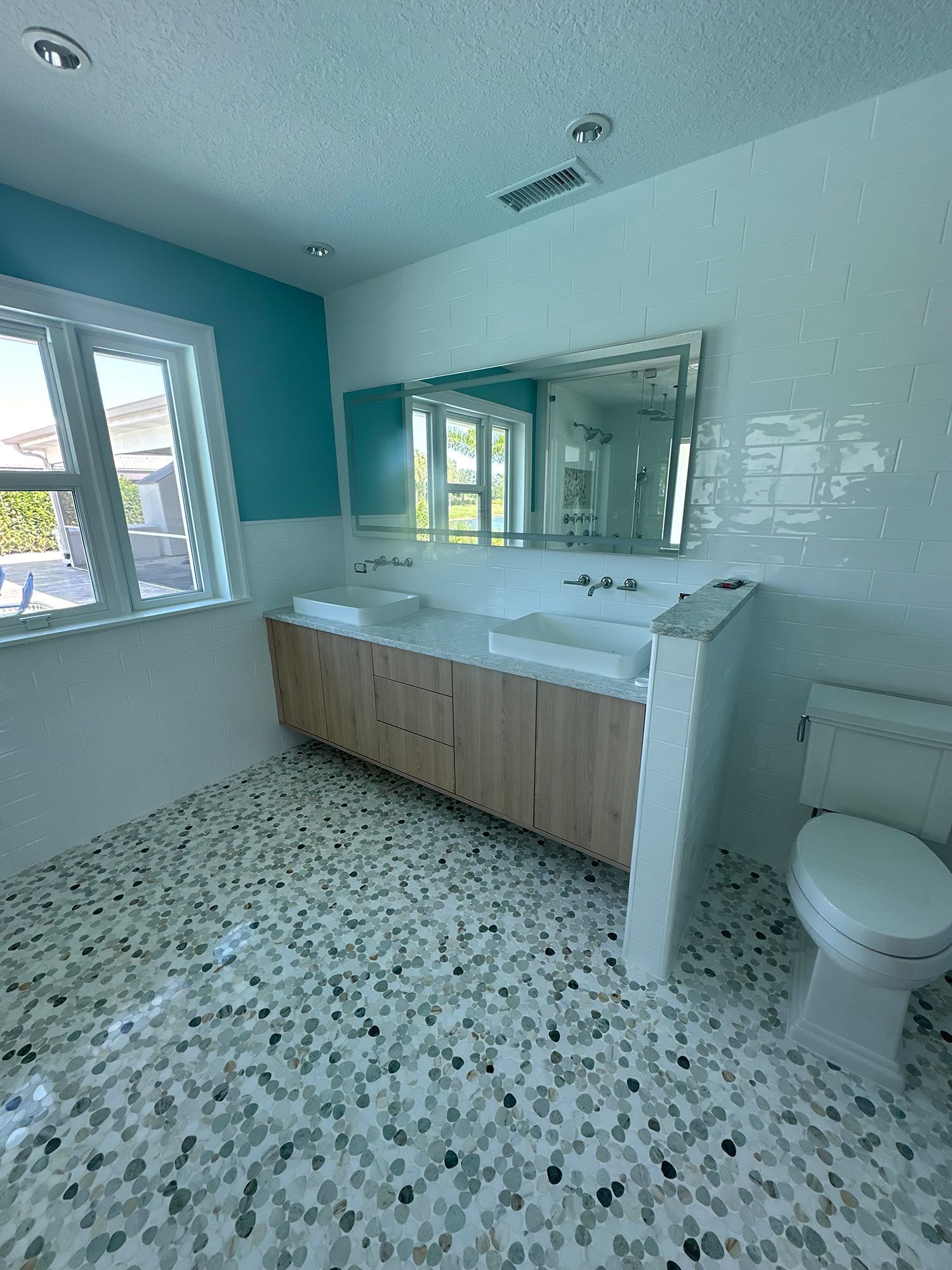 Bathroom with white walls, wood vanity, mosaic tile floor, and a large mirror.