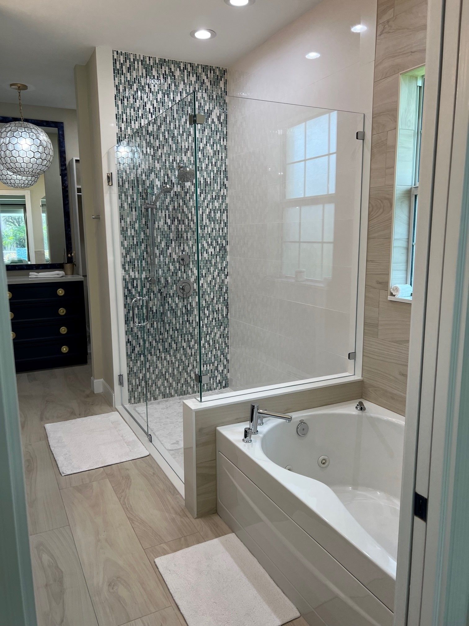 Modern bathroom with glass shower, soaking tub, and mosaic tile accent wall.