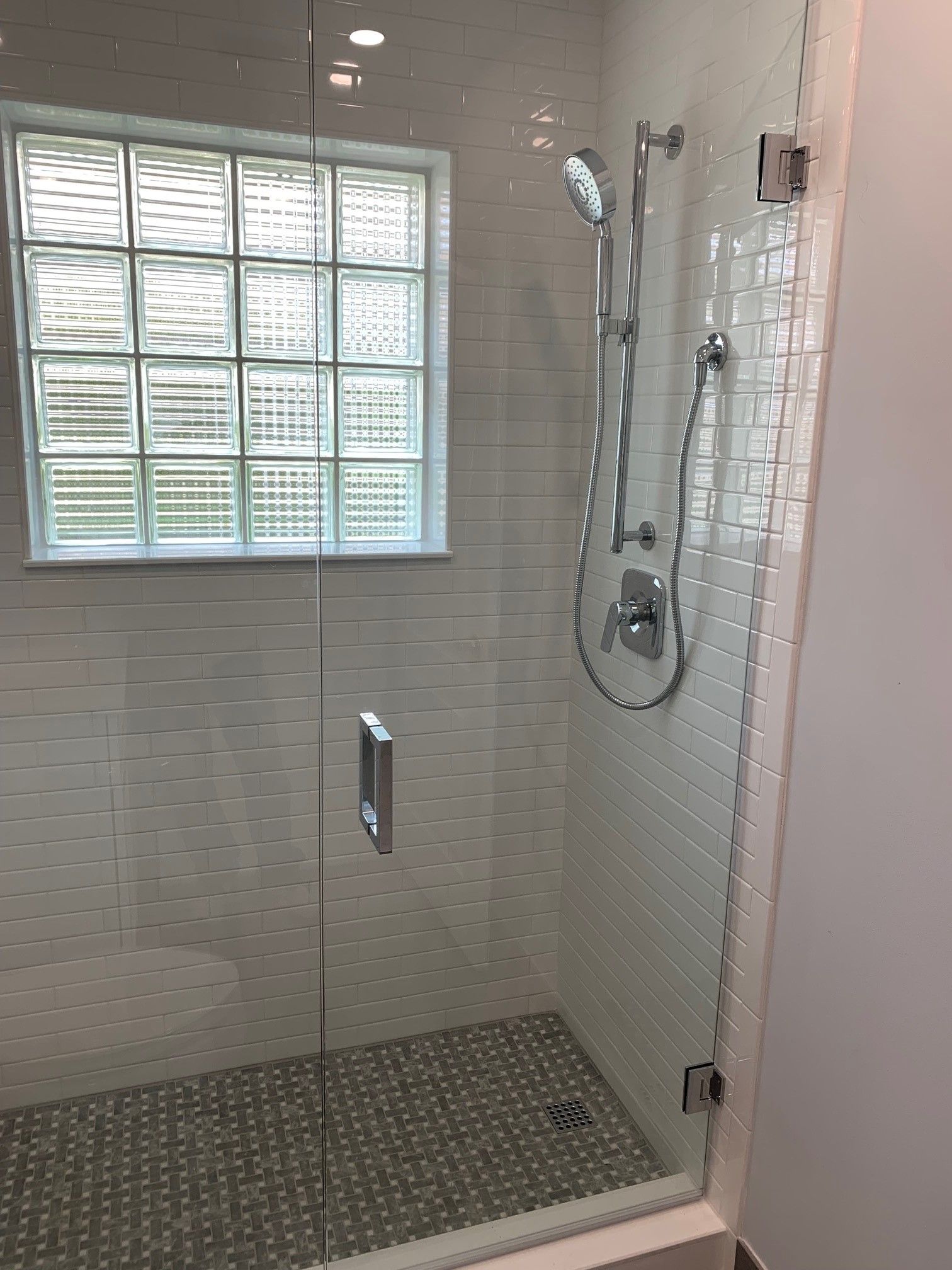 Glass shower enclosure with mosaic tile and window with glass blocks.