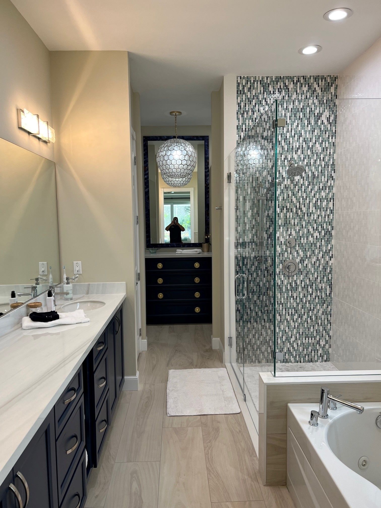 Modern bathroom with vanity, shower, and tub. Teal, white, and gray tile accents with dark cabinets.