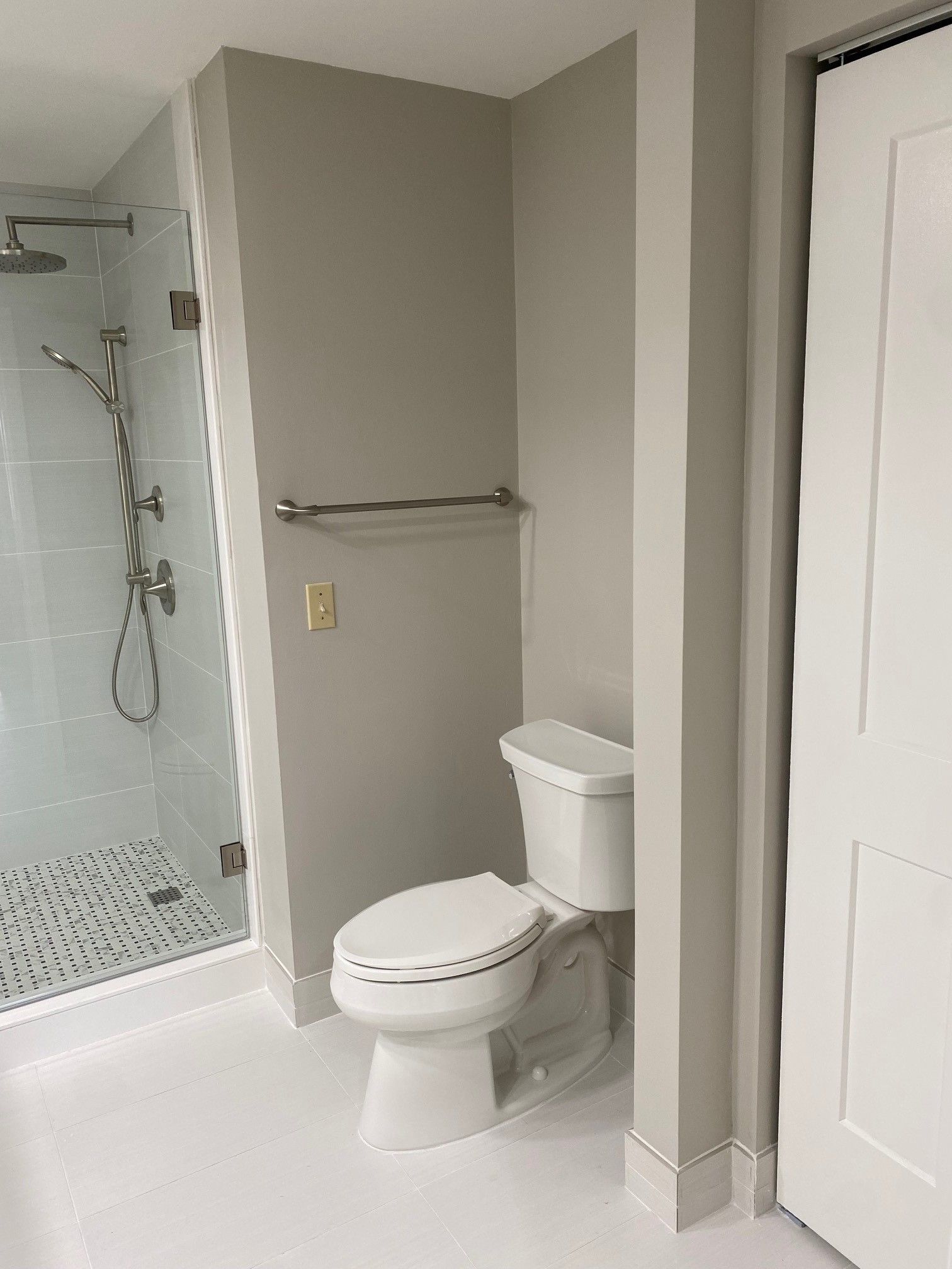 Bathroom with a white toilet, gray walls, and a glass-enclosed shower.