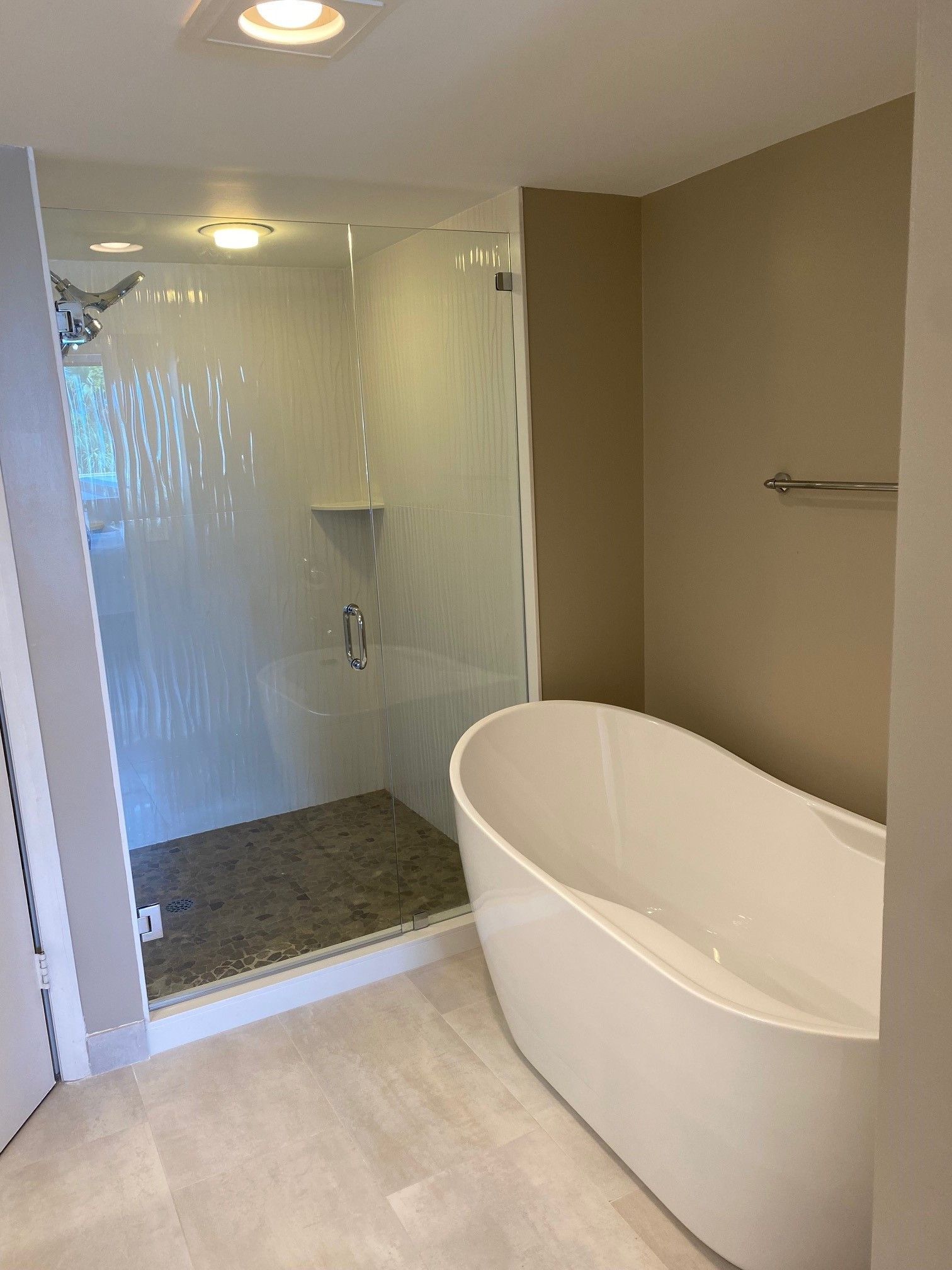 Modern bathroom with a glass shower, a white bathtub, and neutral-colored walls.