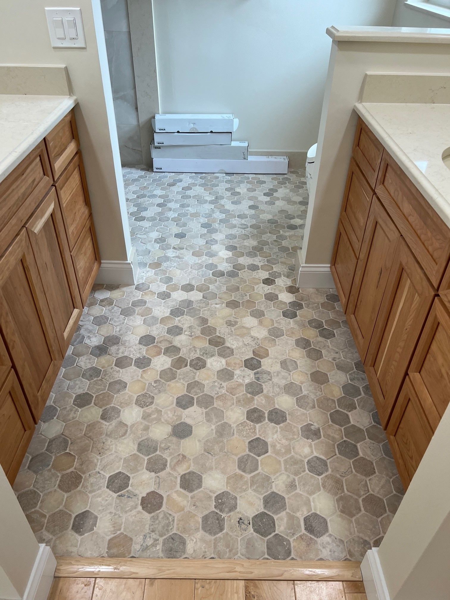 Bathroom with hexagon tile flooring, two wooden vanities, and a doorway.