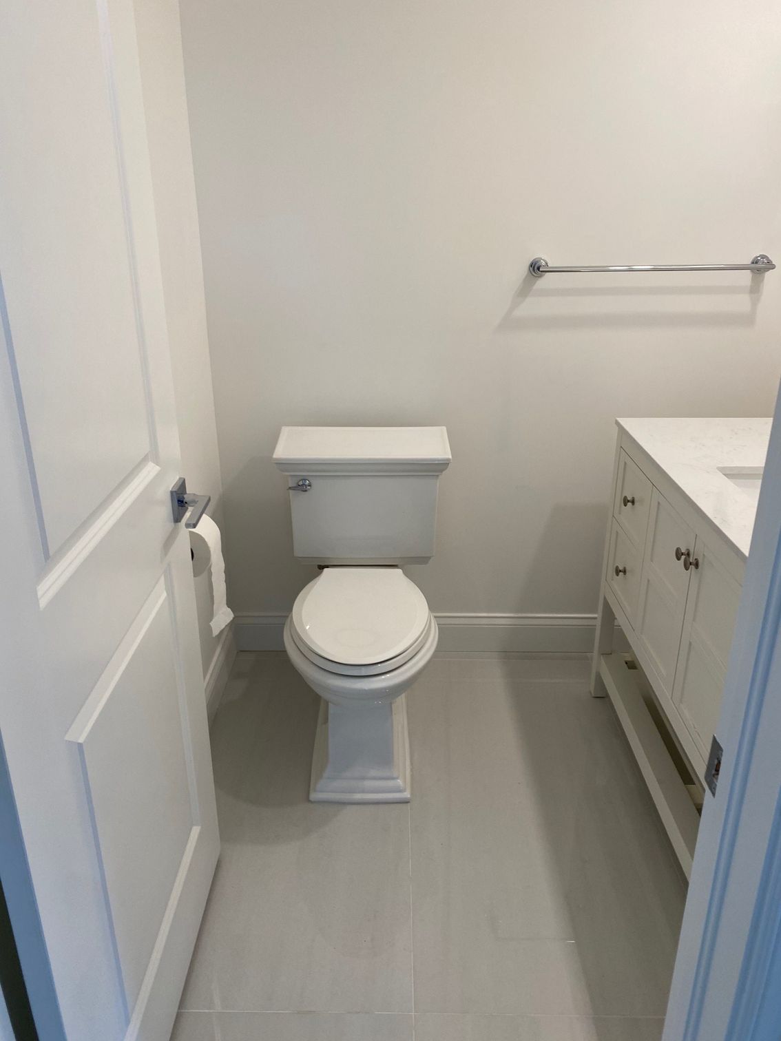 Small white bathroom with a toilet, vanity, and towel rack.