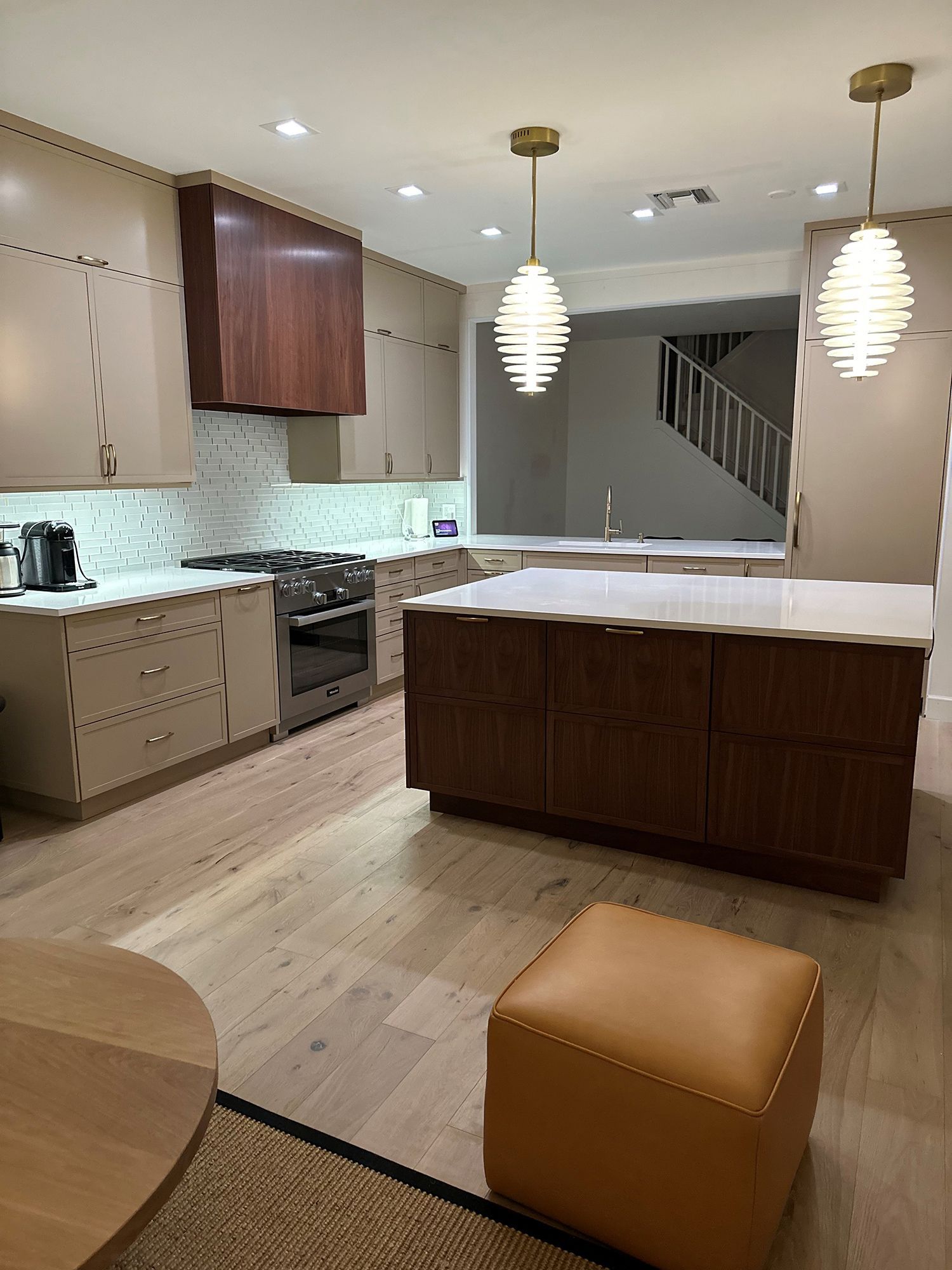 Modern kitchen with light wood floors, brown cabinets, white countertops, and two pendant lights.