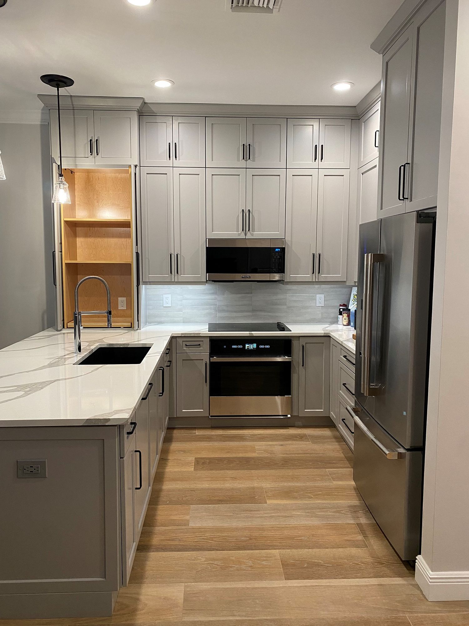 Modern kitchen with gray cabinets, stainless steel appliances, and a white countertop island.
