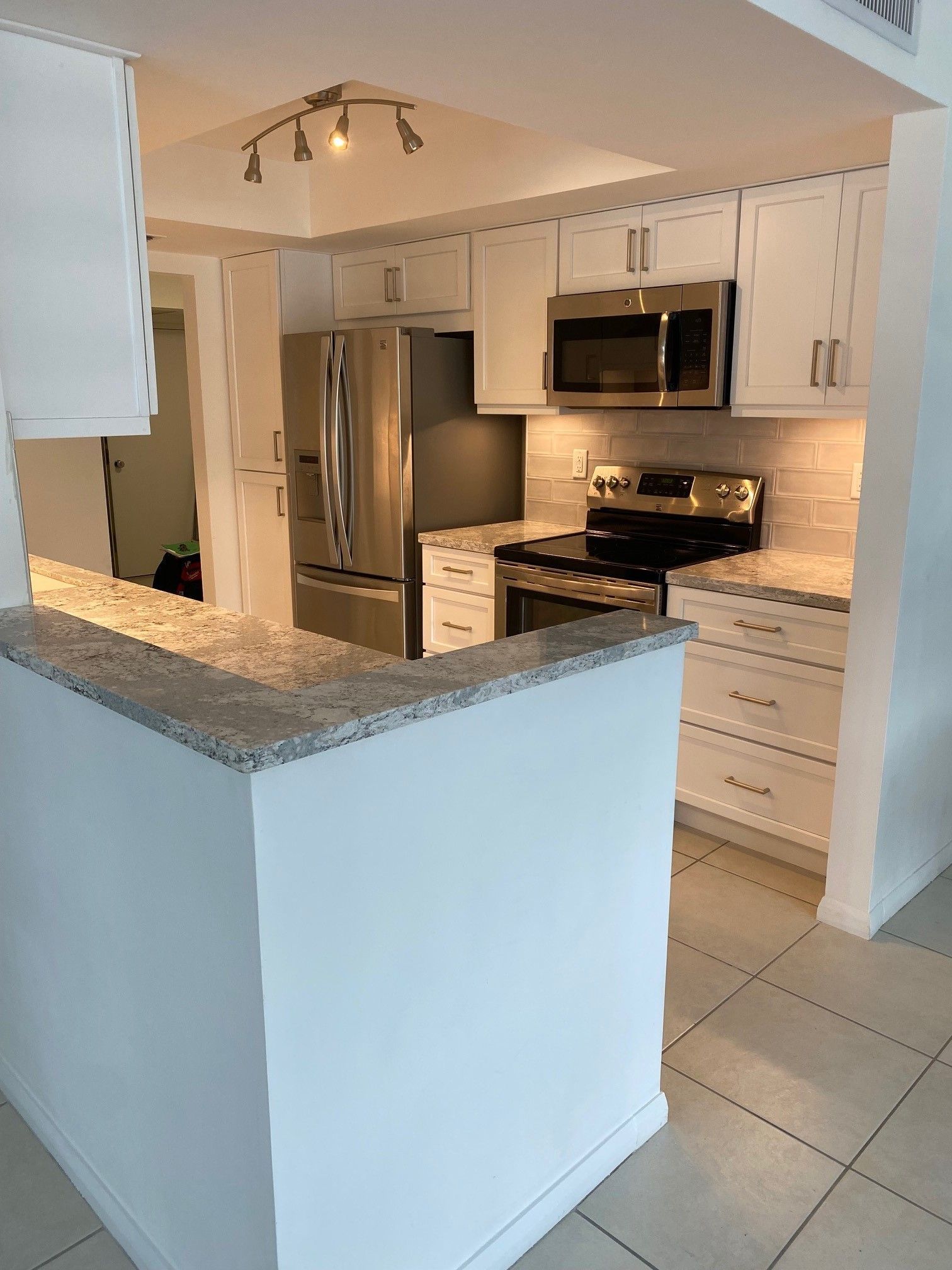 White kitchen with stainless steel appliances, white cabinets, and granite countertops.