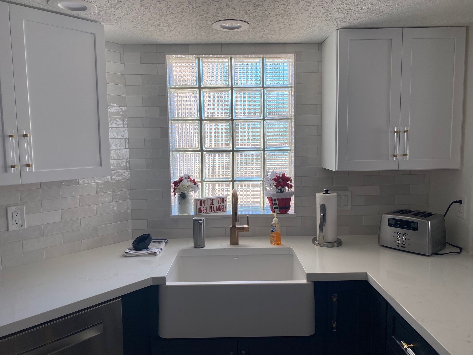 Kitchen with white cabinets, farmhouse sink, and a window with glass blocks.