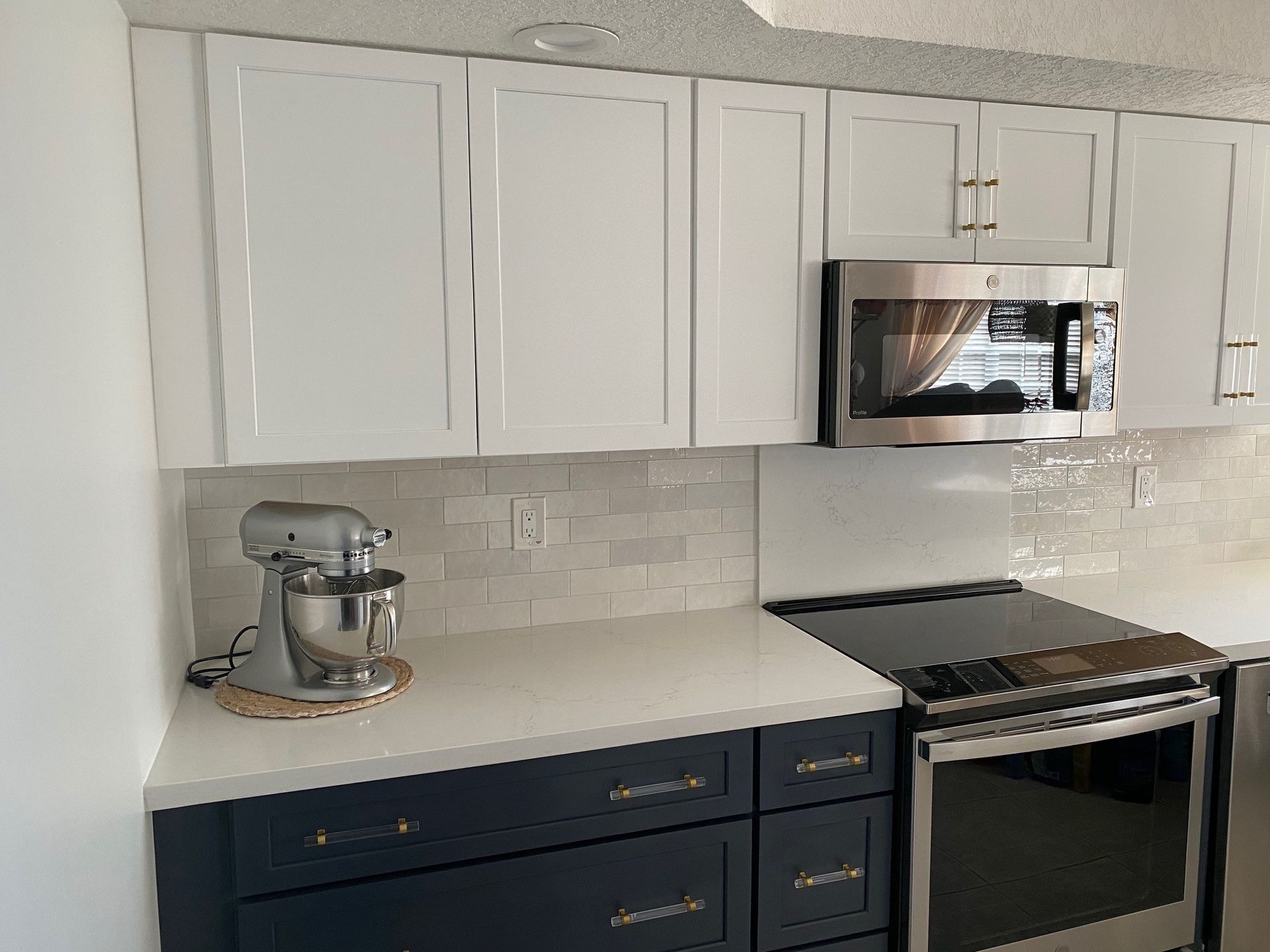Kitchen with white upper cabinets, navy blue lower cabinets, and stainless steel appliances.