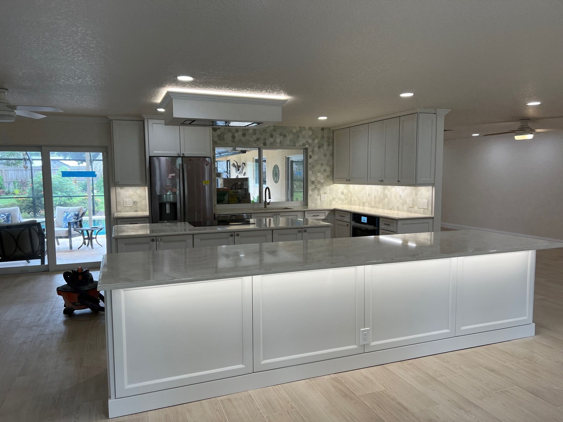 Modern white kitchen with island, quartz countertops, and recessed lighting.