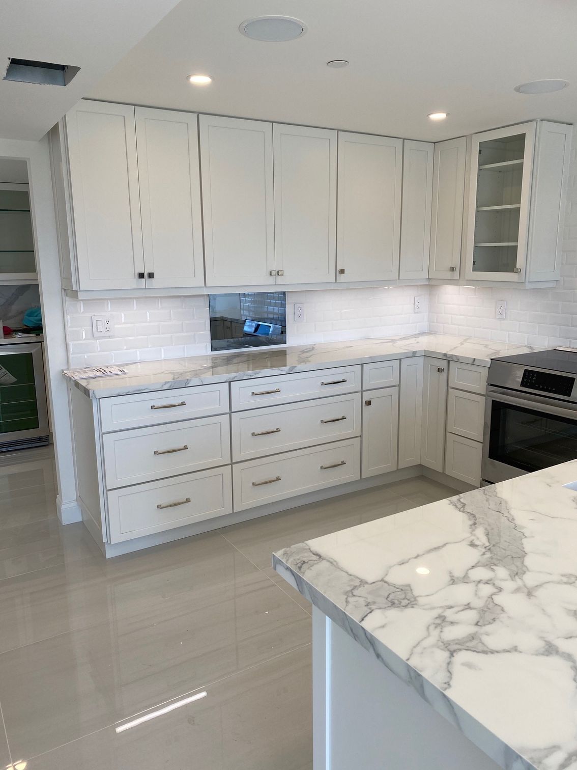 White kitchen with marble countertops and cabinets. Includes an island and built-in oven.