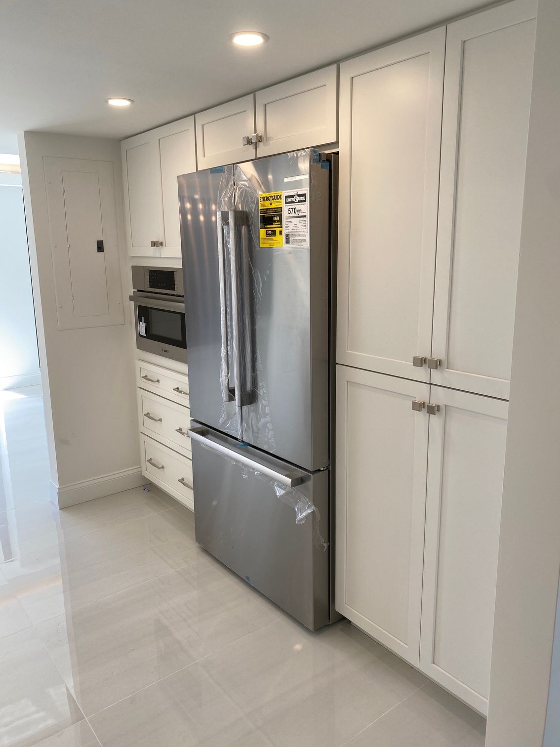 Kitchen with white cabinets, stainless steel refrigerator, and microwave.