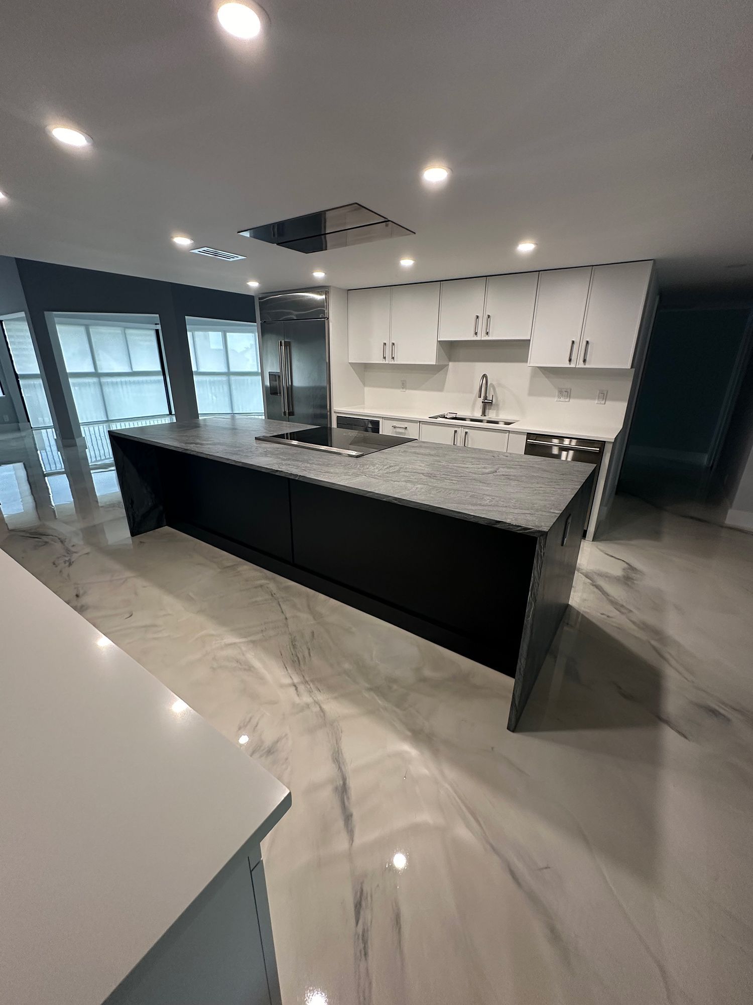 Modern kitchen with black island, white cabinets, and granite countertops.