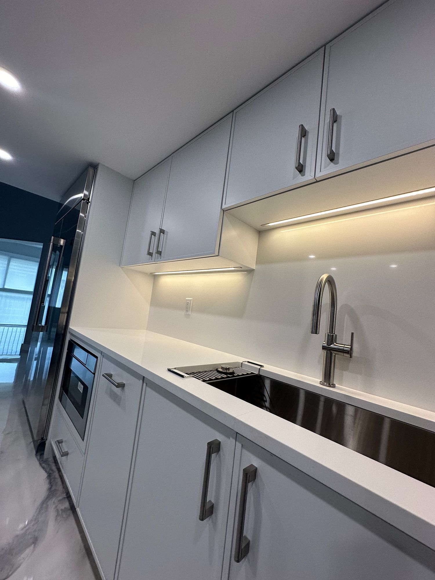 Modern white kitchen with stainless steel sink, countertop, and cabinets.