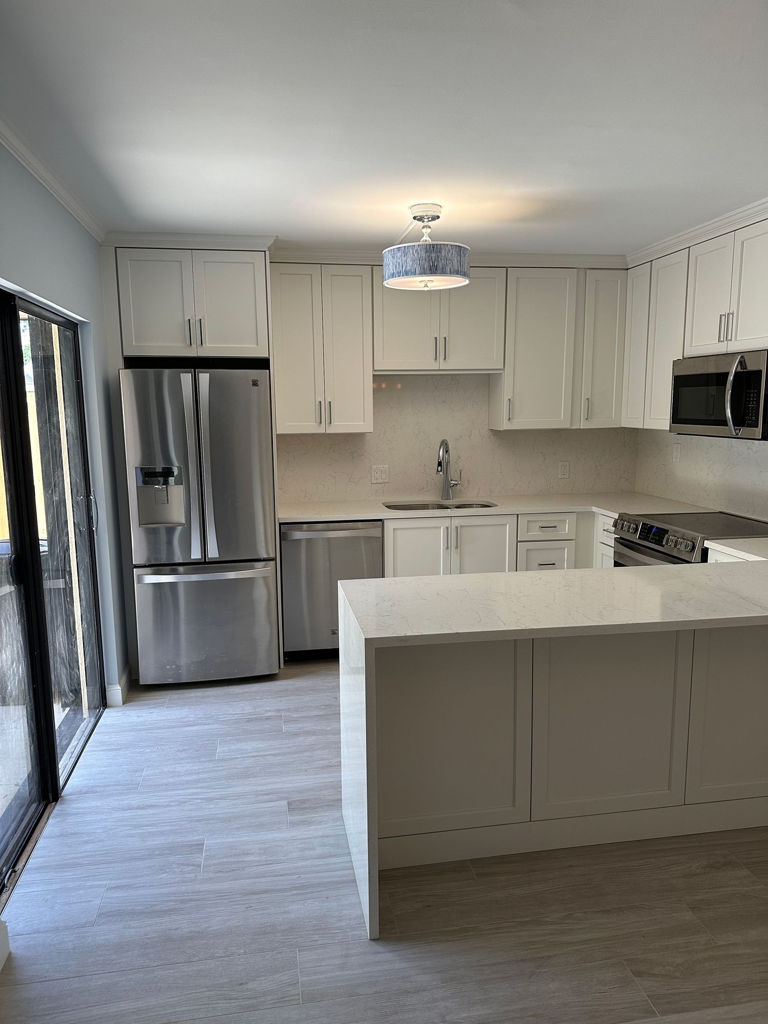 Modern white kitchen with stainless steel appliances, island, and tile flooring.