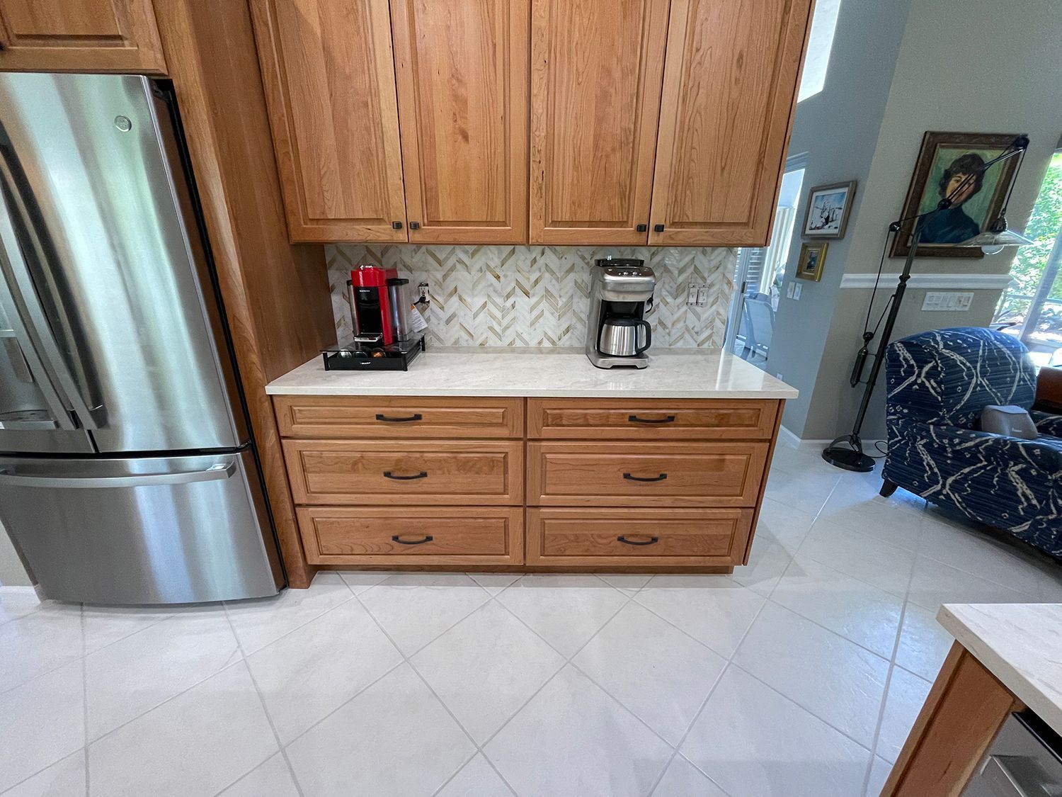 Kitchen with wooden cabinets, stainless steel refrigerator, white countertops, and white tile floor.