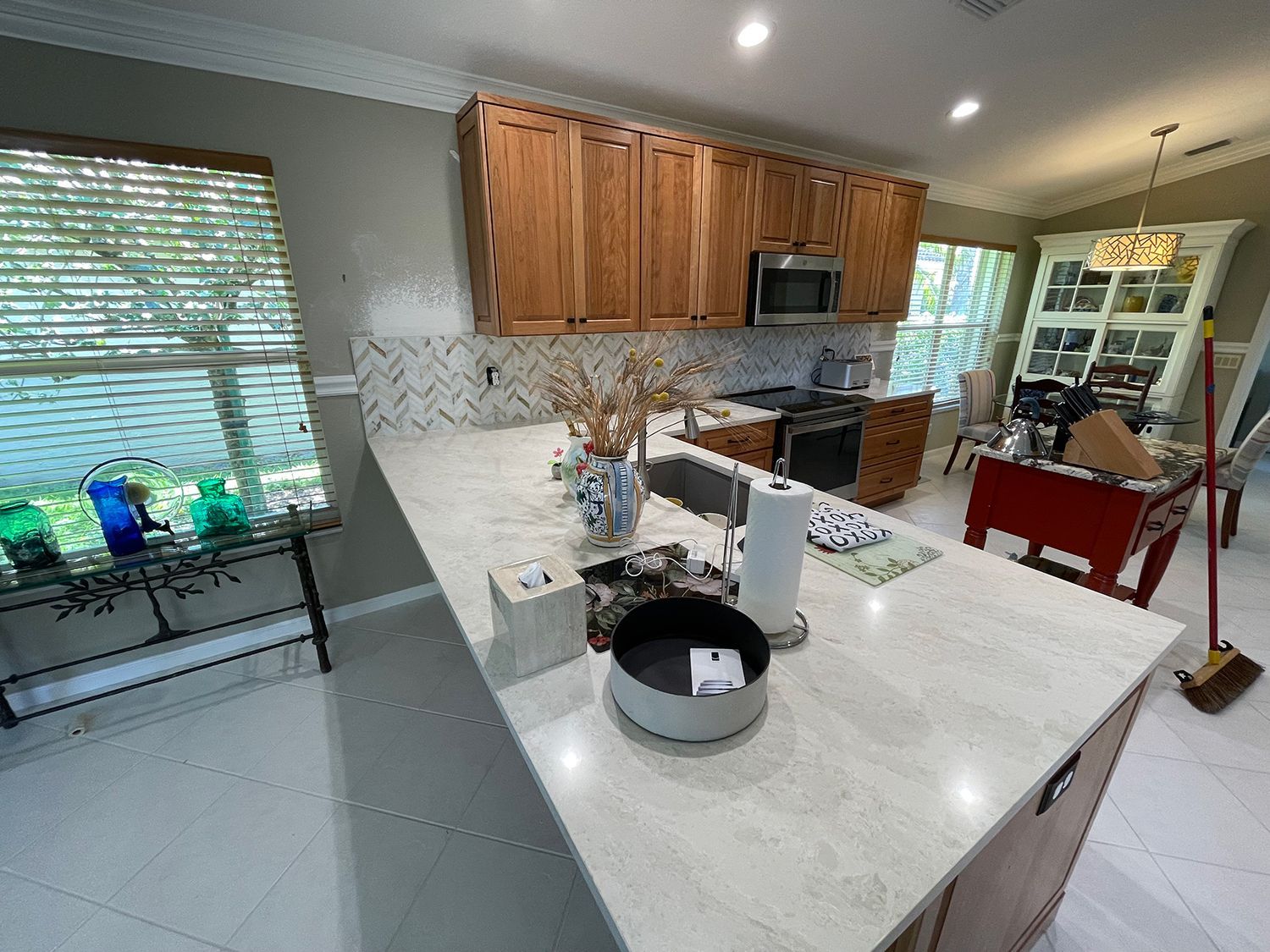 Kitchen with light-colored countertops, wood cabinets, and an island. A microwave and stove are visible.