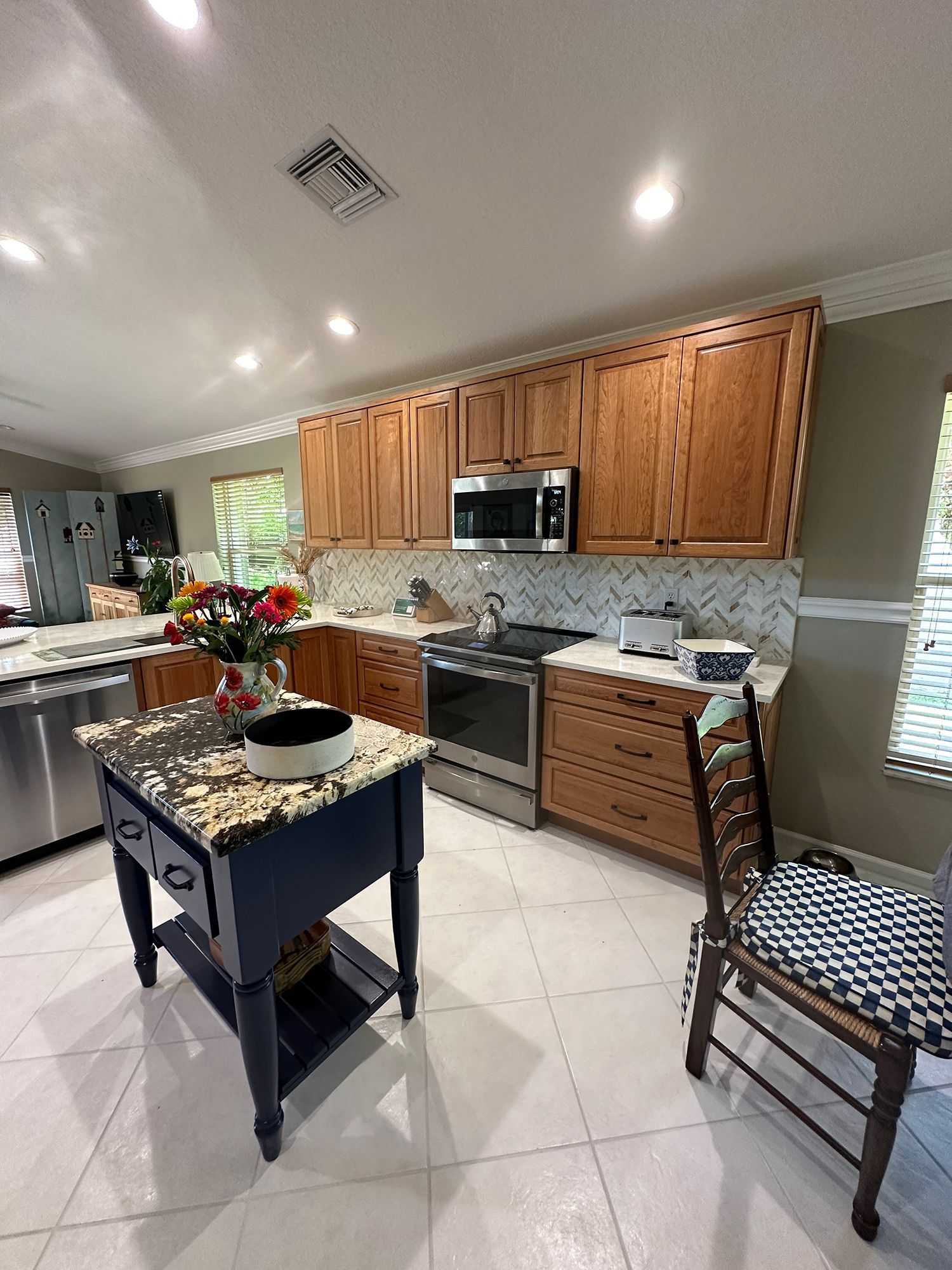Kitchen with wood cabinets, stainless steel appliances, blue island, and white tile floor.