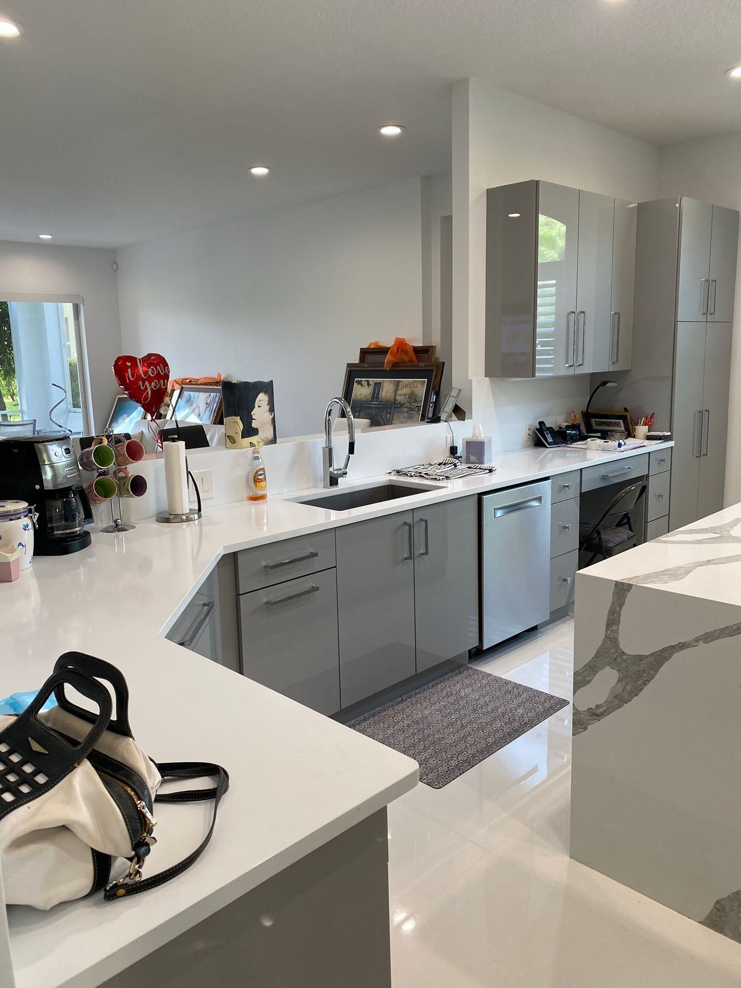 Modern kitchen with gray cabinets, white countertops, and stainless steel appliances.