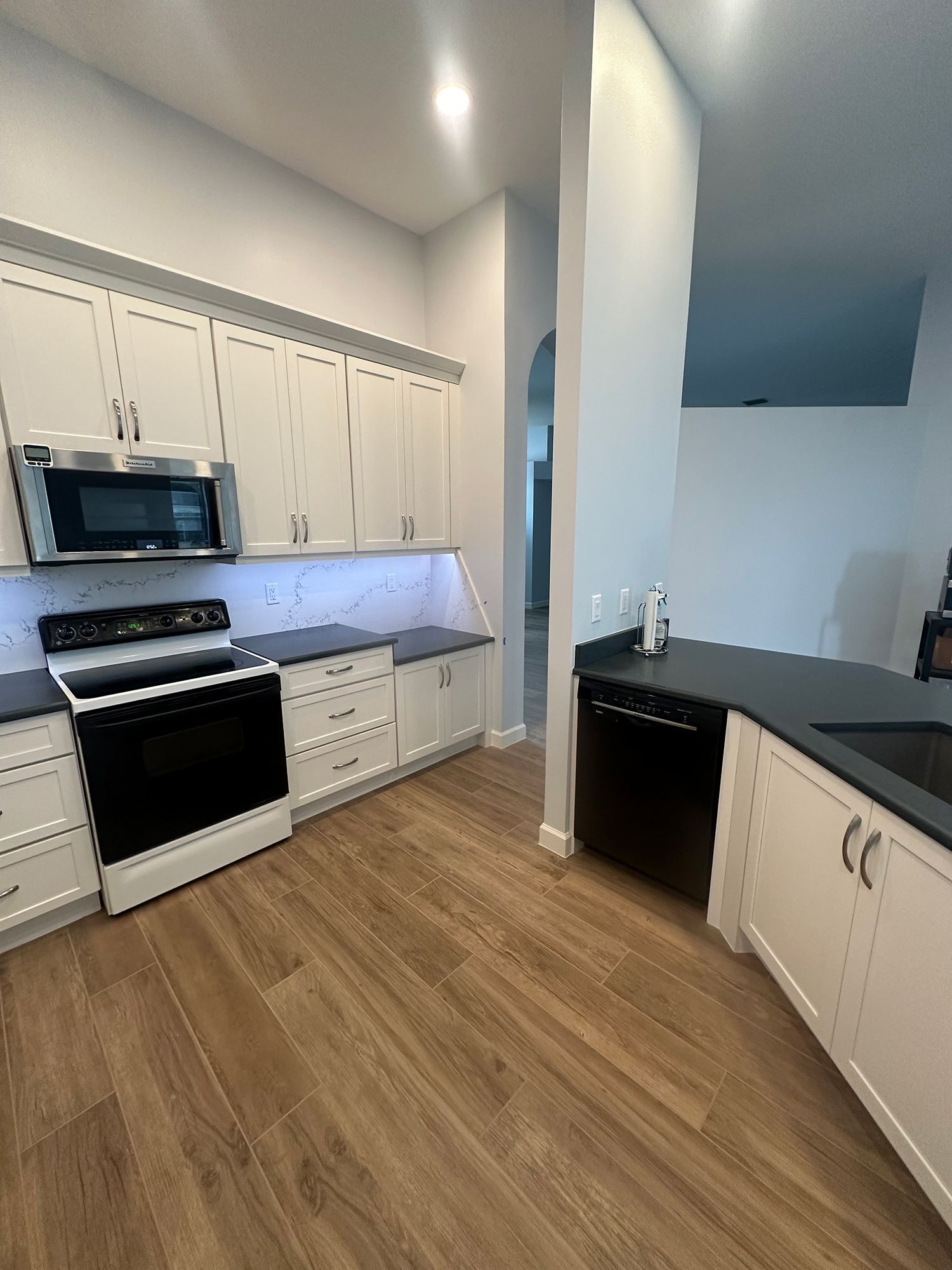 Modern kitchen with white cabinets, dark countertops, and stainless steel appliances.
