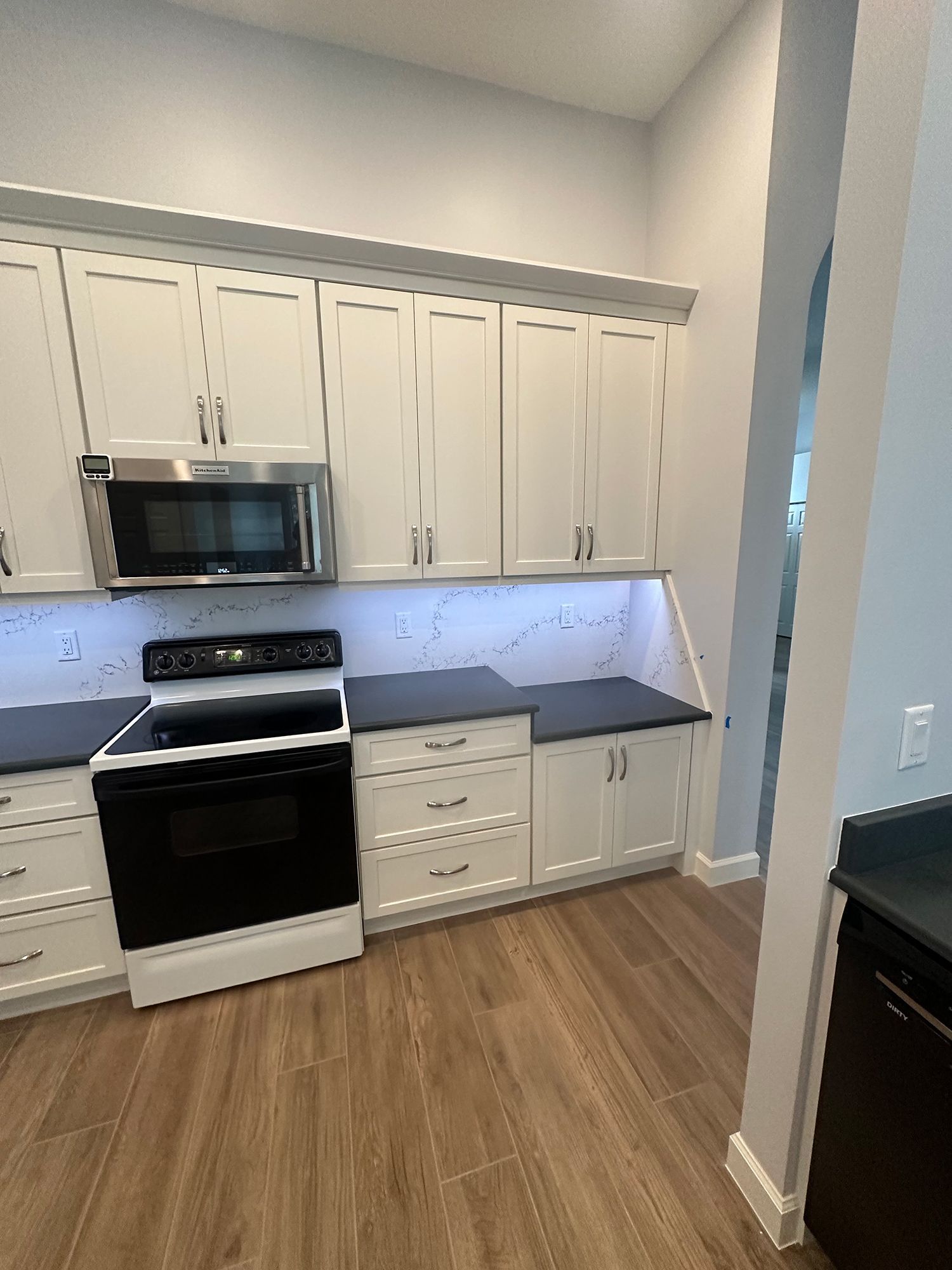White kitchen cabinets with black countertops and black stove.
