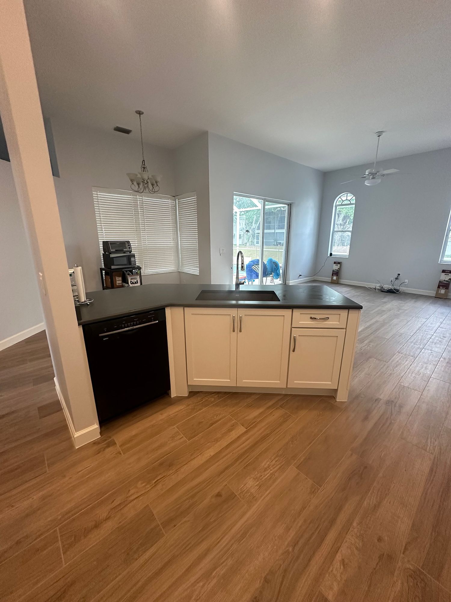 Kitchen with light wood floor, white cabinets, black countertops, and a black dishwasher.