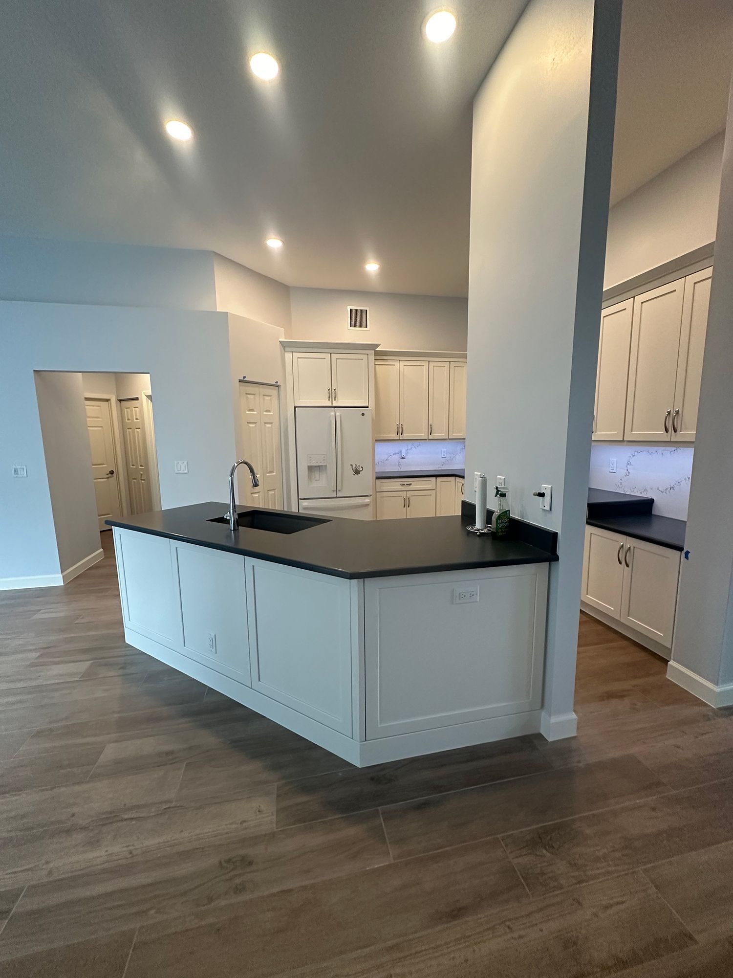 Modern kitchen with white cabinets, dark countertops, and a central island.