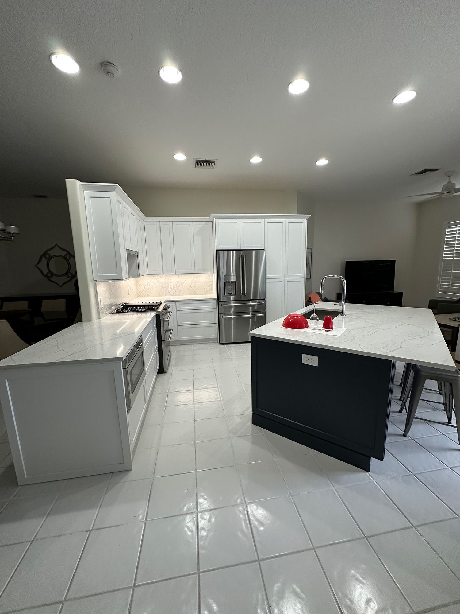 Modern kitchen with white and dark blue cabinets, stainless steel appliances, and a large island with seating.