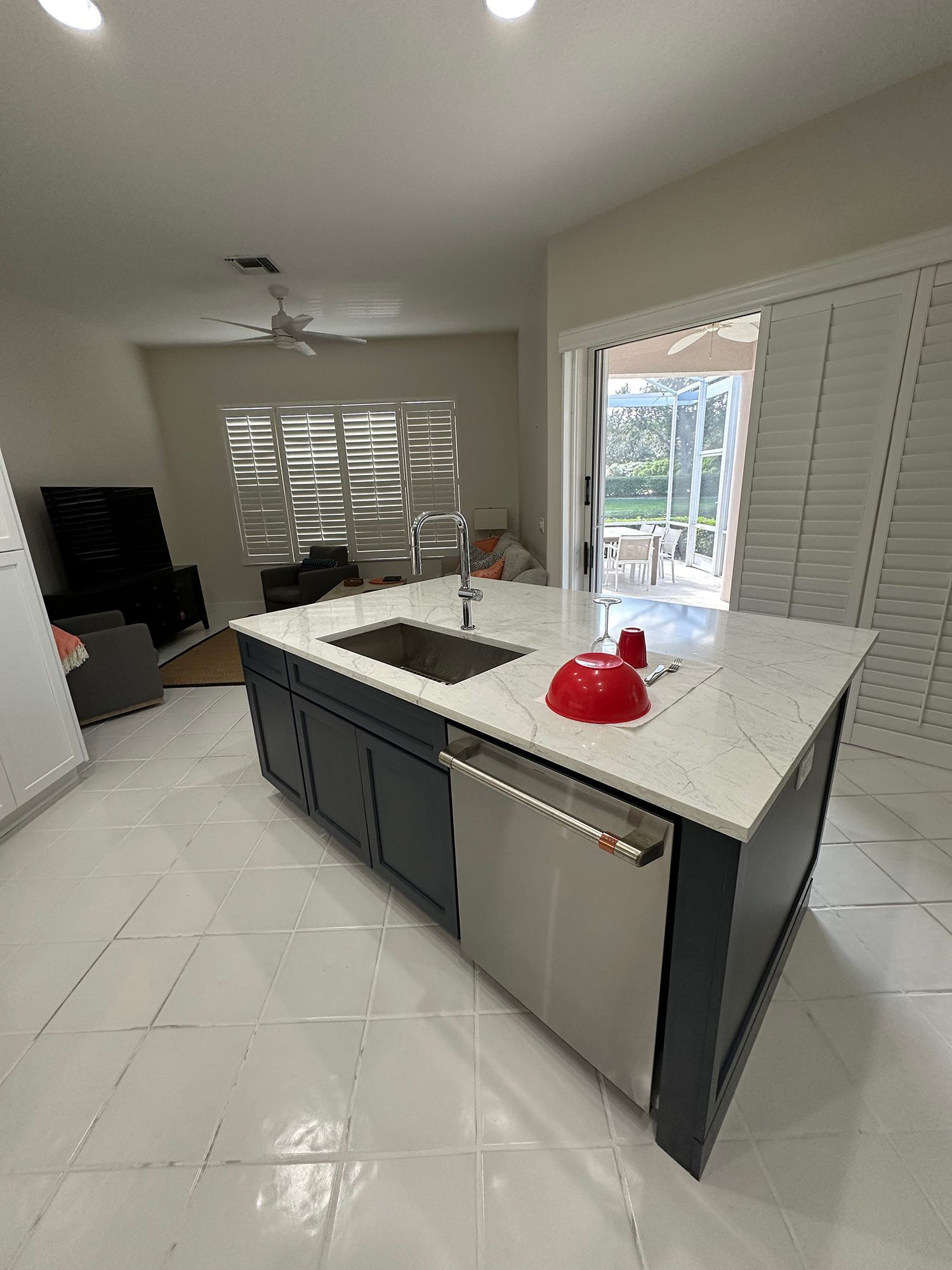 Kitchen island with stainless steel appliances, granite countertop, and dark blue cabinets. Sliding door leads to a patio.