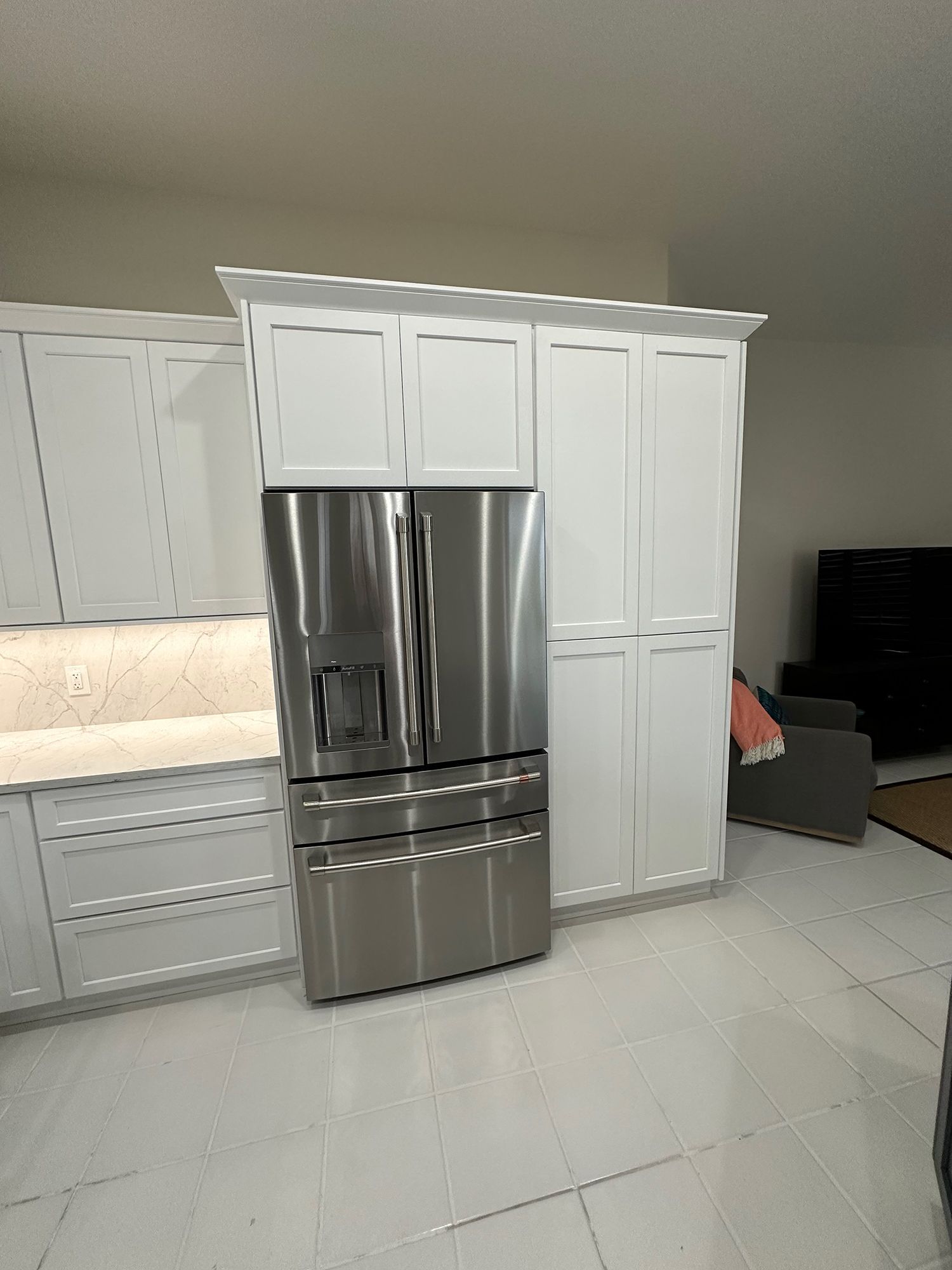 Stainless steel refrigerator in a white kitchen with cabinetry.