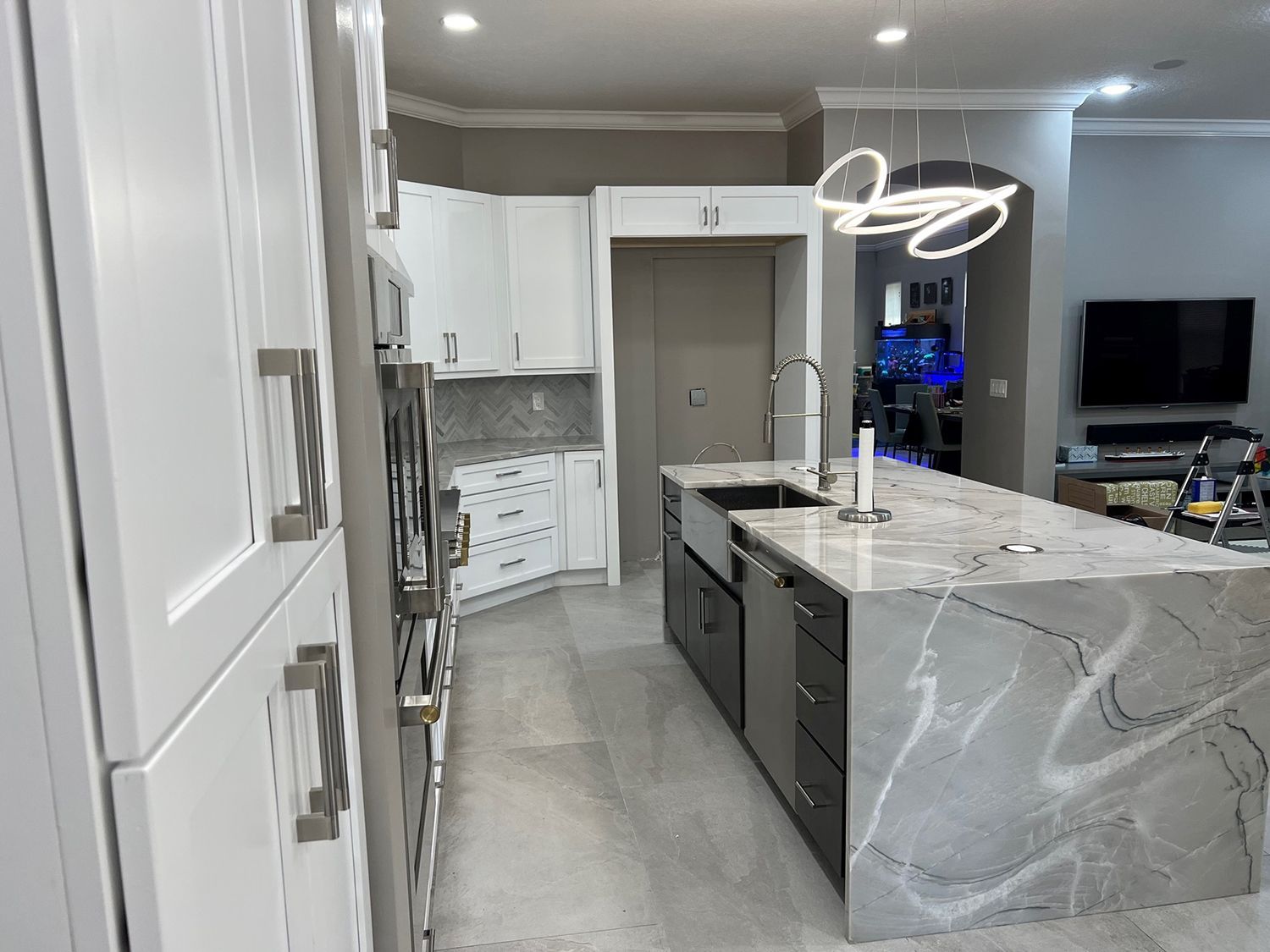 Modern kitchen with white cabinets, gray countertops, stainless steel appliances, and a large island.
