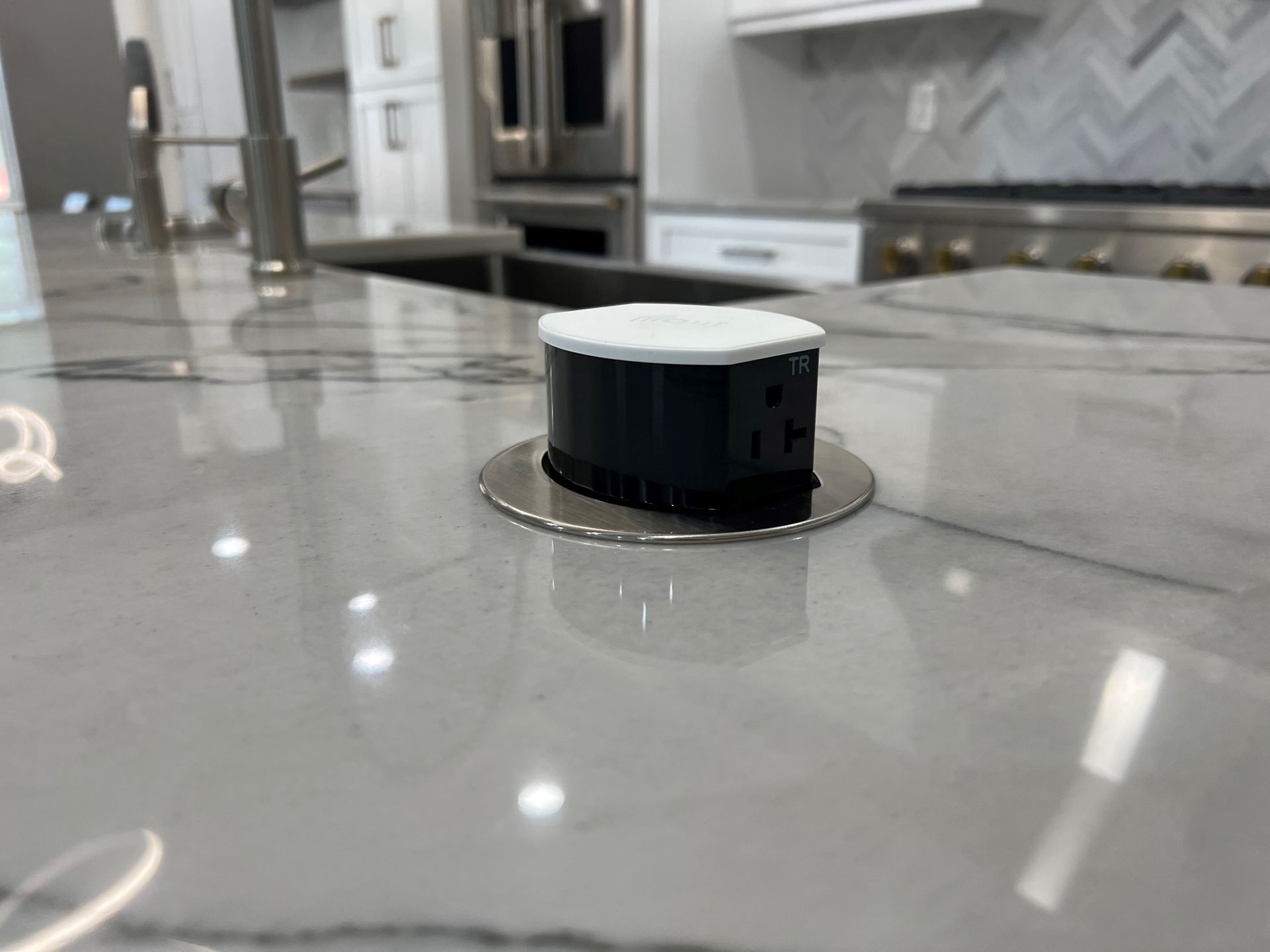 Close-up of a pop-up electrical outlet on a marble countertop in a kitchen.