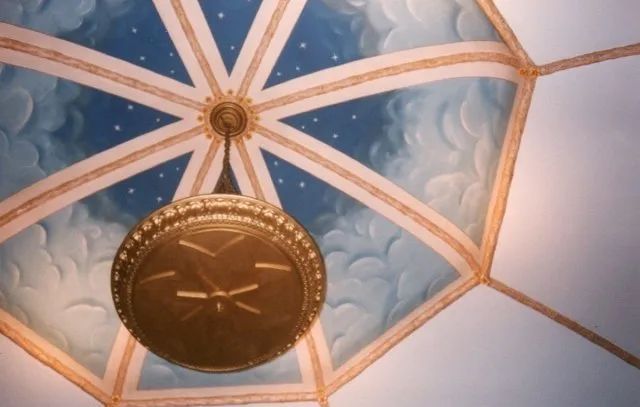 A clock hanging from the ceiling of a building